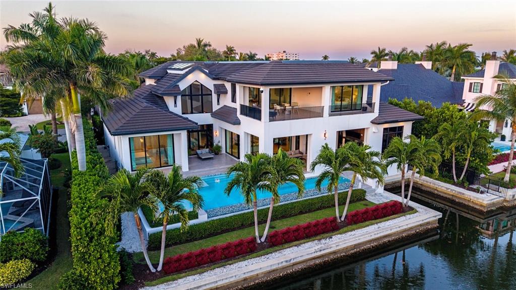Built in 2020, this exceptional waterfront residence—masterfully designed by WDG Architecture and constructed by the Glendale Group—embodies clean, timeless architecture with soaring ceilings, abundant natural light, and highly coveted southern exposure on Crane Channel providing quick and direct boating access to the Gulf of America. Perfectly situated in the heart of Aqualane Shores, the home offers effortless walkability to Old Naples, the boutiques and bistros of Third Street South, and Naples’ world-renowned white-sand beaches. Encompassing over 6,200 square feet of air-conditioned living space, the thoughtfully designed floor plan includes 5 bedrooms, 5 full and 1 half baths, a 3-car garage, heated pool and spa, and expansive covered outdoor living and kitchen areas, all protected with automatic screens and shutters. A 25’ cut-in boat slip enhances the property’s boating convenience and lifestyle. Interior highlights include wide-plank oak flooring throughout, a gourmet kitchen with top-tier appliances, complemented by a separate service kitchen, dedicated wine bar, solid concrete construction, including concrete second floor, generator, multiple fire features, and negotiable furnishings for a potential seamless, turnkey experience. Meticulously maintained by BCB Estate Management, the property is in pristine condition and ready for immediate occupancy.