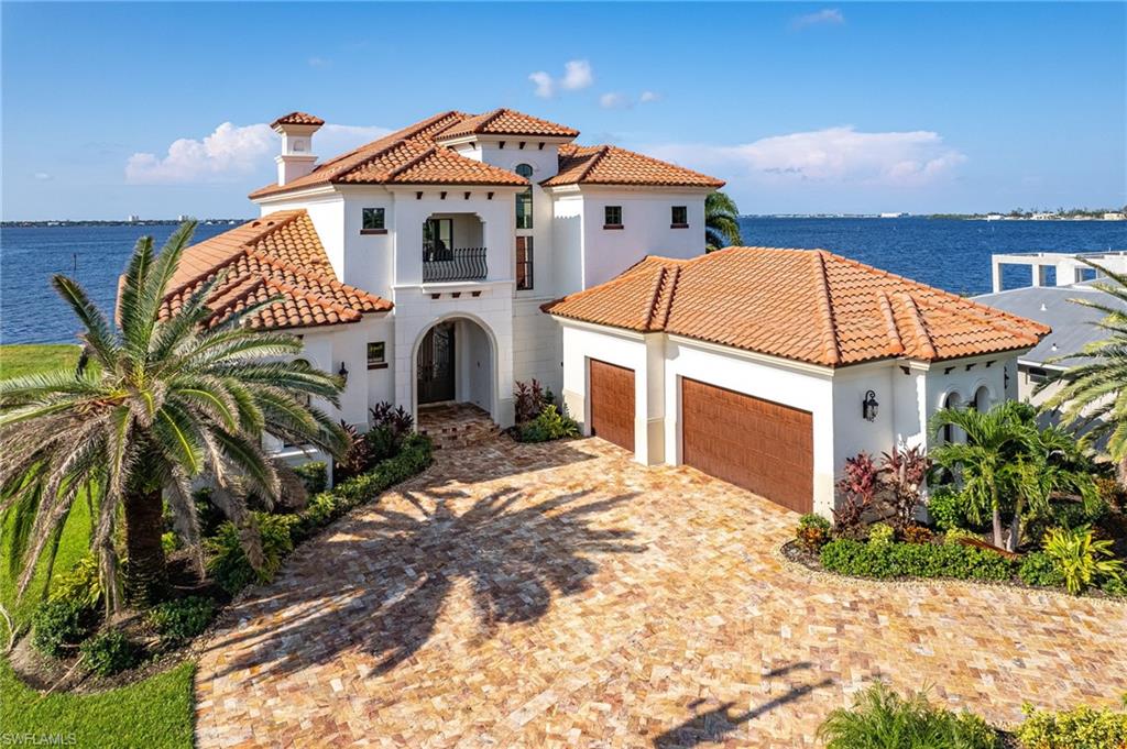 Step inside of Cape Coral's most luxurious custom home that's built like a fortress and crafted like a designer's dream. This waterfront estate captivates you upon entry with its soaring 25' ceilings and riverfront views! This estate known as Villa Brielle comes fully furnished! Located on the most desirable riverfront property in the heart of Cape Coral. Every inch of this luxury 5 bed, 5 bath estate has been purposely designed with your pursuit of happiness in mind. The 26,000 lb boat lift has a new oversized dock merging your days by land and sea. Grill your fresh catch from the fully equipped outdoor kitchen. Dolphins, sunsets, and panoramic river views will become the backdrop of your nautical lifestyle. The refreshing infinity pool and spa sparkles in the sun by day and glows of aqua at night. Flames flicker from the poolside gas fireplace creating resort style ambiance and enchantment throughout the well-manicured grounds. Indoors you'll discover the chef's kitchen has been fully stocked for your convenience and has a gas Viking range. Italian marble countertops, custom appliances, smart home technology, a low assumable flood insurance policy, and a butler’s pantry are just a few of the many custom features you will discover upon visiting Villa Brielle. Come and see why this luxury estate is everything you’ve dreamed about finding in one perfectly designed estate.