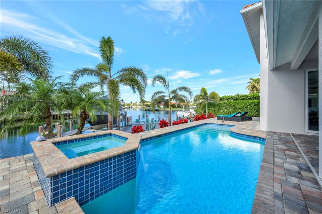 Come and see this spacious 4-bedroom coastal-style home, centrally located on Marco Island! Enjoy wide water views and stunning sunsets. The open floor plan on the first floor features a kitchen with an island and plenty of additional counter space, making meal prep convenient. 

The laundry room includes a separate sink and quartz countertops, along with overhead cabinets for extra storage. A walk-in pantry located off the laundry room, complete with custom shelving, provides ample food storage. The master bedroom suite offers dual walk-in closets, each featuring custom shelving. The master bath has a spa-like feel, equipped with a freestanding soaking tub, a walk-through shower, and dual vanities. 

There is a dedicated space for a home office, plus a flex room that currently serves as a gym. You’ll have easy boating access right from your oversized dock, along with plenty of space to fish or relax. Enjoy ample outdoor living space with a covered lanai and an open patio, perfect for soaking up the sunny days. 

The second floor features three nicely-sized bedrooms, two full baths, and a large covered balcony to take in those beautiful views. This home also includes a brick paver circular driveway and an epoxy garage floor. Don't miss out on this incredible opportunity!