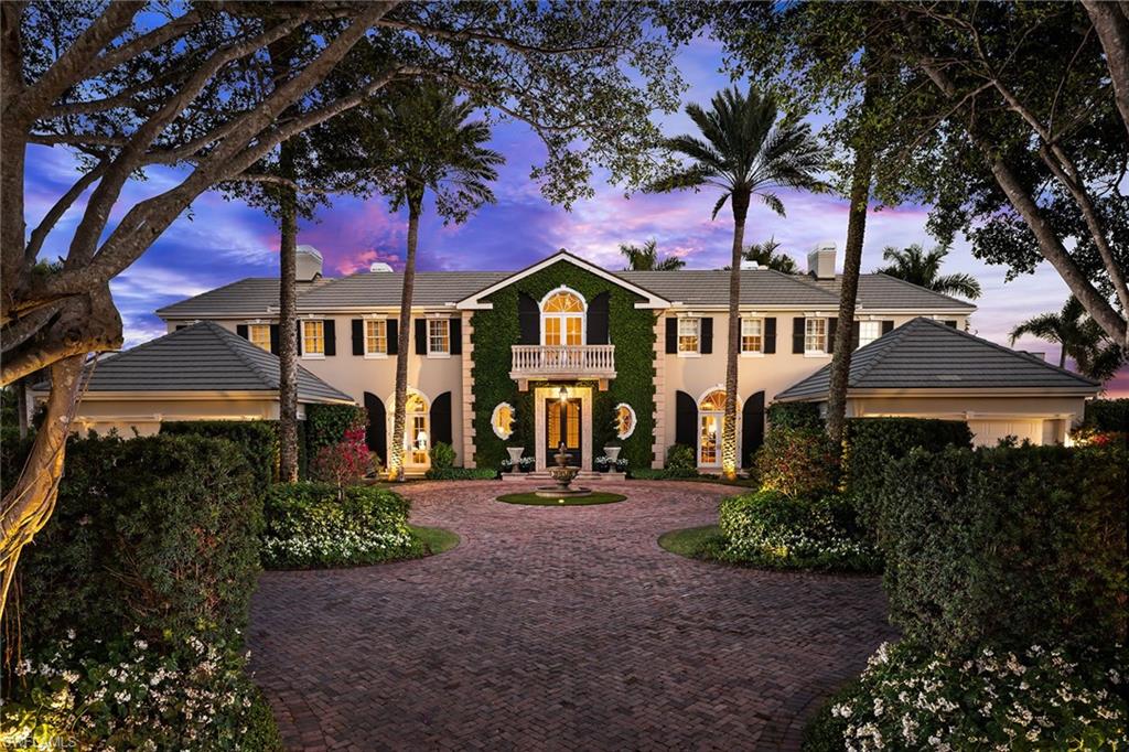 Commanding 268 feet of prime Naples Bay frontage and situated on one of Port Royal’s most admired parcels, this iconic Port Royal residence represents an enduring legacy of architectural distinction and waterfront allure. The spectacular six bedroom, eight bath residence encompasses more than 11,000 square feet of living space, thoughtfully designed to capture panoramic water views from nearly every room. Built in 2005, the home reflects a bespoke blend of Georgian Colonial architecture with Caribbean and Palm Beach influences, resulting in a refined, timeless aesthetic. The residence features a dramatic two-story staircase, gourmet kitchen, formal and casual living and dining spaces, main-floor primary suite and study, elevator, and private theater. Wine storage, a wet bar, and seamless indoor-outdoor flow further enhance the home, with each detail curated to elevate both daily living and entertaining. A guest wing offers independent living with two bedrooms, full kitchen, great room, and private entrance, making it well suited for flexible use or extended visits. Outdoors, the estate’s scale and setting are unparalleled, offering remarkable amenities including a courtyard-style motor court, expansive lanai, outdoor kitchen, ample green space, and a resort-style disappearing-edge pool that blends seamlessly with the horizon of Naples Bay. Completing the waterfront lifestyle is a 93-foot boat dock with direct Gulf access.
This celebrated estate presents enduring distinction in one of Naples’ most sought-after waterfront enclaves, with immediate eligibility for Port Royal Club resident membership.