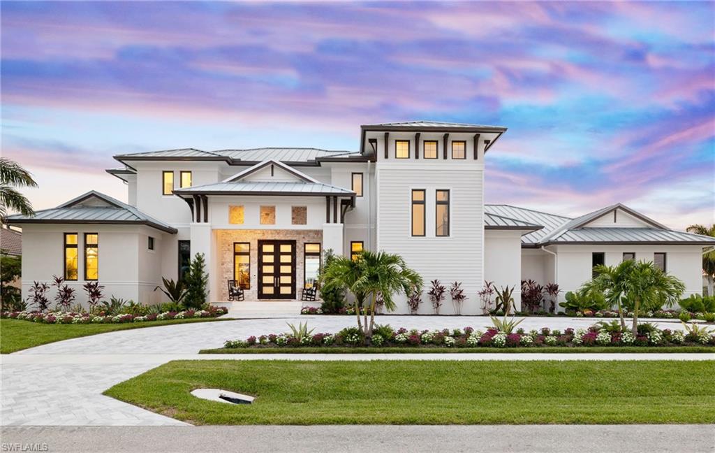 Available for the first time, this recently completed Coastal Organic Transitional masterpiece redefines refined island living. Perfectly positioned on a coveted oversized shoulder lot with rare dual-street access, the home enjoys 270-degree western exposure and sweeping, ever-changing views of Marco Island's magnificent coastal skyline.

Spanning approximately 4,700 square feet, this newly constructed estate delivers exceptional scale, abundant natural light, and a timeless architectural presence. A dramatic open-plan entry immediately draws the eye through expansive walls of 10-foot hurricane-impact retractable glass sliders, seamlessly dissolving the boundary between indoors and out. The horizon becomes part of the home—framed by a striking glass-tile pool with shell-stone stepping features, flowing effortlessly to an infinity-edge spa. Surrounded by lush, custom landscaping, the setting is a private coastal sanctuary.

The residence offers five en-suite bedrooms, a dedicated office, and six spa-inspired baths, thoughtfully designed for both elegance and comfort. Additional highlights include a full laundry room designed for sandy toes, a modern elevator, and a generous second-floor living area with sunset terrace, ideal for evening gatherings and golden-hour views.

Outdoor living is equally exceptional, featuring a resort-style pool and spa, outdoor kitchen with bar and dining area, and a convenient outdoor shower—perfect for long, breezy afternoons. A three-car garage includes potential separate guest or private quarters, enhancing flexibility and privacy. The home is crowned with a durable metal roof and equipped with a Tesla charging station, blending luxury with forward-thinking functionality.

Inside, European white oak wide-plank flooring flows throughout, setting a warm, organic tone. The chef's gourmet kitchen is outfitted with top-of-the-line appliances and anchored by a custom-designed wine showcase that commands attention and elevates entertaining. The primary suite is a true retreat, complete with a spa-level bath and expansive walk-in shower, delivering a daily resort experience.

This custom home reflects a natural, organic foundation—where stone, texture, coastal hues, and curated seaside photography tell a distinctive story. Every detail is intentional, beautifully choreographed to capture a fresh, modern coastal rhythm of life.