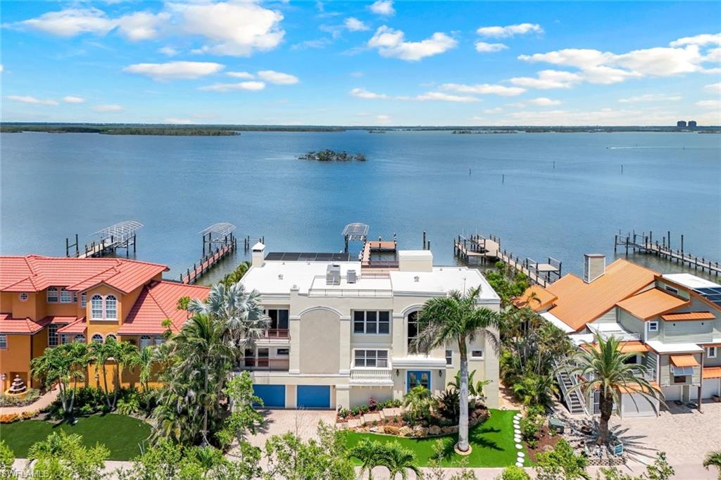 Sweeping Estero Bay views set the stage for this exceptional 4-bedroom, 3.5-bath BAYFRONT retreat offering the ultimate Florida lifestyle with every amenity imaginable.  The top-level main living space is built for entertaining, with fully pocketing sliders that bring the bay into full view. An open layout flows seamlessly from the gourmet kitchen, featuring two islands, premium appliances, and a handy dumbwaiter, to the living room with wet bar, wood-burning fireplace, and retractable screened balcony perched high above the bay. The owner’s suite offers a private sanctuary with a wall of glass showcasing the waterfront view, a spa-like bath, and a massive walk-in closet with a California Closet system. Two additional bedrooms, a bath, and laundry are also located on the middle level, with a fourth bedroom and full bath tucked upstairs for added privacy.  Outdoor living shines here: on the first level, a screened-in pool with a swim-up bar, hot tub, separate bath, and shower, along with expansive patio areas, creates a true resort vibe. You'll also find an oversized 2-car garage with epoxy floors and built-ins, and a recreation room.  For boating enthusiasts, a composite dock with two lifts and a personal watercraft lift offers quick, direct Gulf access. Cruise to waterfront restaurants at Fort Myers Beach or escape south to Lover’s Key.  Additional features include an elevator with a view window, rooftop access with 360° panoramic vistas, two  A/C units, and incredible storage throughout.