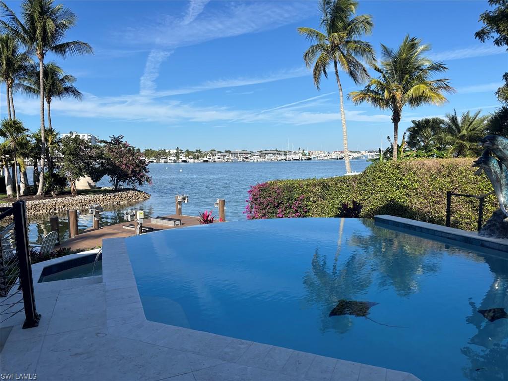 Welcome to Florida living at its finest. From the moment you enter this Coastal-style residence, breathtaking, unobstructed views of Crayton Cove and Naples Bay create an unforgettable first impression that never fades. Soaring ceilings, granite tile and new hardwood floors, designer lighting, and fresh interior and exterior paint set the tone for refined coastal elegance throughout.  The updated kitchen and luxurious primary suite—complete with a spa-inspired bath, floating soaking tub, and stunning walk-in closet—are just a few of the many thoughtful enhancements in this exceptional home. Offering nearly 7,700 total square feet, the residence features four bedrooms plus an office, four full and two half baths, a spacious media room, and a private elevator.
The great room opens seamlessly to the outdoors through full-corner hurricane-impact sliding doors, creating effortless indoor-outdoor living. Plus Generac back up generator to cover whole house.  Enjoy the first-floor infinity pool deck as boats glide by en route to the Naples Yacht Club, or embrace the ultimate boating lifestyle with direct Gulf access and no bridges. The new 18,000-lb covered boat lift, double jet-ski lift, and 50-amp shore power complete this boater’s paradise. A three-car garage with air conditioning and two custom 6,000-lb car lifts adds exceptional convenience.  Unwind on the second-level terrace with new Ipe wood decking while taking in iconic Naples sunsets, or practice your short game on the private putting green—all surrounded by spectacular water views. Designed for luxurious living and unforgettable entertaining, this one-of-a-kind waterfront residence delivers the very best of the Naples lifestyle.