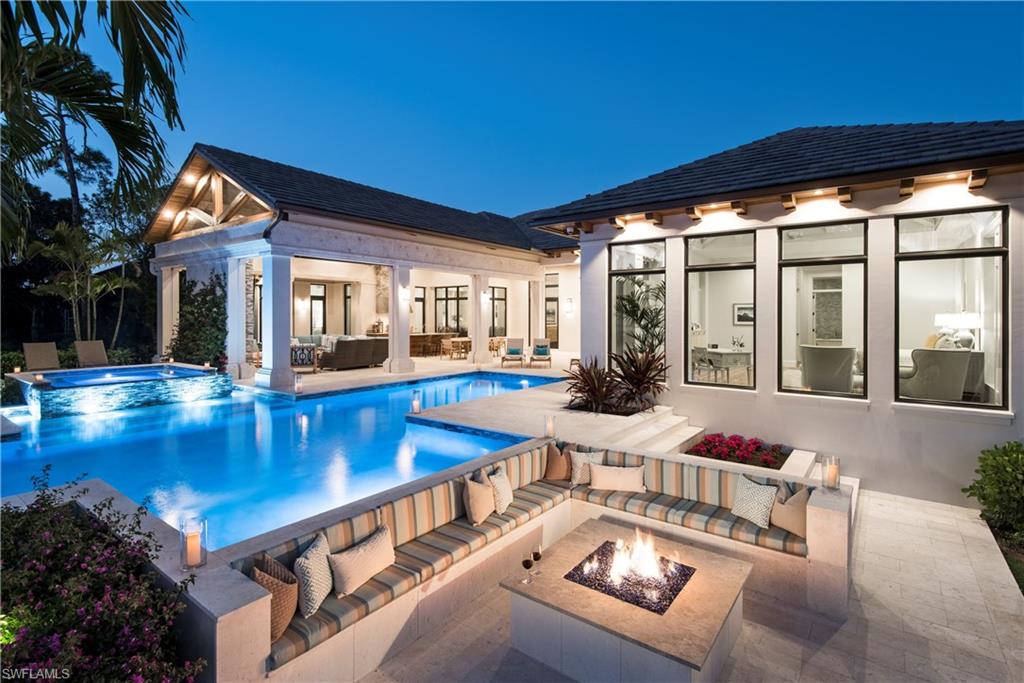 Discover refined coastal luxury in this exceptional estate within the prestigious gated enclave of Georgetown at Pelican Bay. Perfectly positioned on a rare half-acre homesite, the residence enjoys expansive lake and golf course views with ideal western and southwestern exposure, creating breathtaking sunsets and abundant natural light throughout the home. Built in 2016 by Knauf-Koenig Group with architectural design by Stofft Cooney Architects and interiors by Calusa Bay Design, this four-bedroom plus office residence spans over 5,200 square feet under air and blends timeless elegance with sophisticated modern living. A welcoming architectural entry leads through impact-rated mahogany French doors into light-filled interiors defined by soaring ceilings ranging from 11 to 15 feet and refined custom millwork. The great room creates a dramatic yet inviting central gathering space, where wide-plank European oak flooring and thoughtfully designed built-ins establish warmth and architectural character. Three sets of French doors open seamlessly to the outdoor living areas, perfectly framing tranquil lake and fairway vistas while blending indoor and outdoor living with effortless elegance. At the heart of the home, the chef’s kitchen is designed for both everyday living and exceptional entertaining. Custom floor-to-ceiling cabinetry, a stunning Cristallo quartzite island, and a full suite of Sub-Zero and Wolf appliances anchor the space. A spacious butler’s pantry provides additional prep space and storage, while the wet bar features wine refrigeration and beverage drawers for effortless hosting. A built-in banquette surrounded by windows offers a relaxed dining space overlooking the pool and outdoor pavilion. The primary suite offers a serene private retreat with sweeping lake and golf course views, two generous walk-in closets, and a spa-inspired bath featuring dual vanities, an elegant soaking tub, expansive walk-in shower, and separate water closets. Three additional guest suites provide luxurious accommodations for family and visitors, while a dedicated office and media room offer flexible living and entertainment spaces. Outdoor living unfolds as a private resort. A spectacular 45-foot saline pool with raised spa is surrounded by expansive sun decks, lush landscaping, and a dramatic sunken fire pit lounge overlooking the water. The covered outdoor pavilion features a fully equipped summer kitchen, dining area, and inviting seating space anchored by a linear fireplace and stone feature wall—perfect for year-round entertaining and relaxed evenings. Residents of Pelican Bay enjoy an unparalleled lifestyle with exclusive access to three miles of private white-sand beaches, beachfront dining, tennis and pickleball facilities, scenic walking paths, and world-class amenities just moments from Naples’ finest shopping, dining, and cultural destinations. 
This is Pelican Bay luxury—private, timeless, and designed for exceptional coastal living.