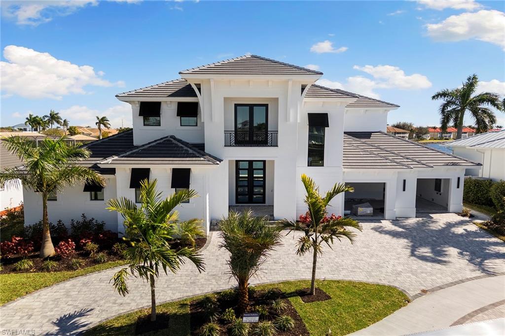 Immerse yourself in the epitome of coastal contemporary living with this exquisite two-story custom-built home, offering four bedrooms, four baths and a den. On a picturesque lot with stunning converging wide water views, this residence is a haven for the boating enthusiast, providing easy access to the Gulf of Mexico with the raised Smokehouse Bridge and on a tranquil cul-de-sac. A spacious open great room with soaring high ceilings, seamlessly blending into a gourmet kitchen. This culinary masterpiece features an island, breakfast bar, custom cabinetry, top-of-the-line Thermador appliances, a six-burner gas range and a separate dining area. The primary suite retreat, on the first floor, offers ultimate comfort and luxury. Additional guest bedrooms on the second floor include a loft, a wet bar and a private balcony, providing a getaway for visitors. The expansive open lanai with a pool, spa, summer kitchen, sun deck and gas fireplace are ideal for entertainment and relaxation, allowing you to indulge in sparkling wide water views. This home is equipped with impact windows and doors, electric shutters for the covered lanai, rolldown screens, generator and propane tank. A new seawall was completed in April 2024, ensuring peace of mind and longevity. Convenient to all Marco Island has to offer, this residence boasts an estimated completion date of March / April 2026, promising a modern, luxurious lifestyle in a great location.