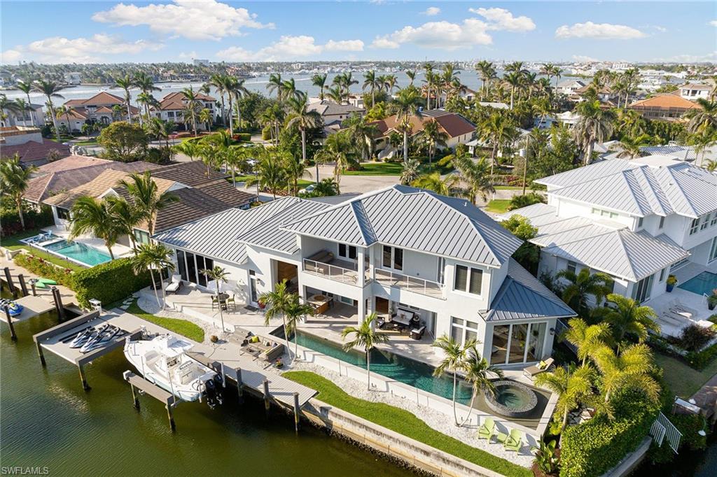Spectacular Royal Harbor custom home on a quiet cul-de-sac boasts southern exposure and over 150’ of deep water direct access, just minutes to the Gulf of Mexico and under 2 miles to downtown 5th ave – a prime spot for boating enthusiasts. This 4-bedroom residence with panoramic waterfront views via its transparent walls, ensures seamless indoor-outdoor living. Dive into the saltwater pool with a lap lane, unwind in the vast spa, all nestled amid tropical flora ensuring seclusion. Inside, high ceilings, oak floors, and exquisite walnut cabinets enhance its luxurious feel. The chef's kitchen is adorned with a Thermador gas range, twin islands, and a roomy pantry. For seamless hosting, there’s a butler's pantry adjacent to the dining and family room. Here, warmth is added by a gas fireplace and a custom wine cooler storing over 250 bottles. The first-floor primary suite is a haven, offering water views and an opulent bathroom. The upper level reveals a secondary VIP suite and another ensuite with a terrace showcasing breathtaking views. For enthusiasts of recreational gear, a 4-car garage offers generous storage potential. Welcome to the epitome of Naples luxury resort living.