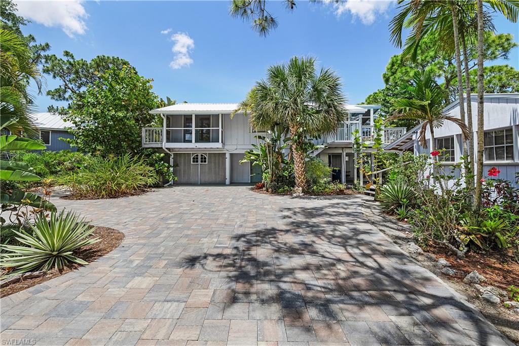This waterfront stilt home and guest house are on a big, beautiful, property with lots of lush vegetation and a pond. The main living area is upstairs and gives the feeling of living in a treehouse. The home has beautiful wood planked cathedral ceilings and wood flooring The lovely, tiled bathroom has a jetted soaking tub and multiheaded shower. The upstairs living area is surrounded by connected decks and screened patios with a large, screened area off the kitchen which is perfect for enjoying the breezes and watching the birds and wildlife around the pond.  A new outdoor lift, drain field and pavers on the circular driveway all add to the value of this property. The upstairs windows are all protected by manual hurricane shutters.  The 1-bedroom guest home is connected by the boardwalk, has a full bathroom and kitchen as well as its own deck for outdoor relaxation. Downstairs under the main living area is a multipurpose room that is perfect for an office, studio or extra bedroom.  It has an additional full bathroom and French doors that open up to a covered deck area.  There is an enclosed 1 car garage with plenty of storage and space for a workshop.  This fabulous home is located at the center of Pine Island and is within easy walking distance of the public pool, playground, library, and local museum. It is just minutes from shopping, and restaurants.  This fabulous home combines natural beauty with functional living spaces, making it the perfect retreat. Schedule a visit today to experience the charm and tranquility of this exceptional property!