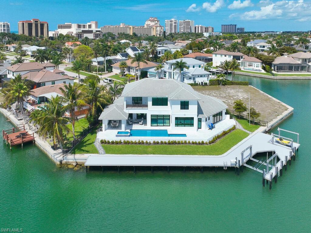 Experience the pinnacle of waterfront living at 999 Spruce Court.  This magnificent, custom-built home located on a highly desirable tip lot offers 5 bedrooms plus den, 5 and half baths, 3 car garage, 169' of waterfrontage, spectacular wide water views and is only minutes from Marco Island's pristine white sand beach.  Upon entering the home, you will immediately be impressed by the soaring ceilings, dramatic staircase, luxurious finishes, and stunning views.  The gourmet kitchen features custom cabinetry, large center island, gas cooktop, and spacious walk-in pantry.  The main-floor master suite is a private retreat with access to the lanai and spa-like ensuite bath with dual vanities, walk-in shower, and custom walk-in closet.  Guests will enjoy the convenience and privacy of the spacious cabana bedroom suite on the main floor featuring water views, lanai access, and ensuite bath.  The second story boasts a large family room with wet bar, 3 additional guest bedrooms with ensuite baths, and balcony.  The main living space of the home opens seamlessly to the spacious lanai.  The covered area of the lanai features an outdoor fireplace, summer kitchen, multiple seating areas, and the convenience of rolldown screens.  Enjoy soaking up the Florida sunshine and relaxing in the beautiful pool and spa overlooking the water.   The new dock (2026) and seawall (2021) with a 20,000lb lift and 6,000lb platform lift will delight boating enthusiasts and fisherman alike.  The gorgeous, tropical landscaping and outdoor lighting create instant curb appeal.  Do not hesitate to make this impressive home your slice of island paradise.