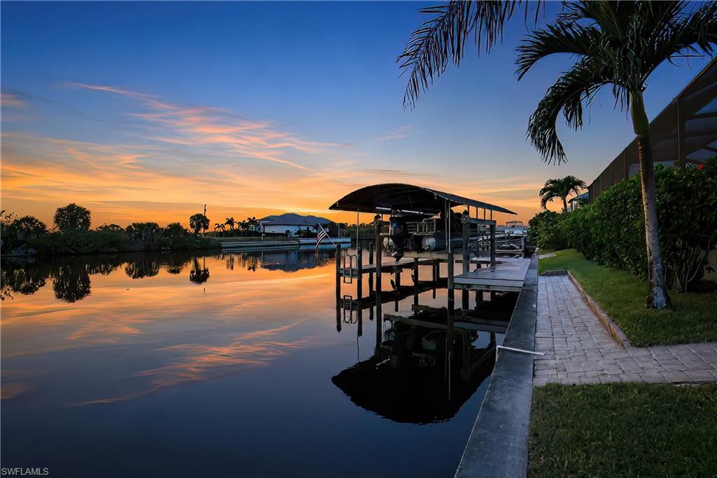 This custom-built home is loaded with EXTRAS and UPGRADES. The home features a large three car garage, whole house solar system which powers all your needs and even puts money back into your pocket (See recent LCEC bill attached). Water flows through a whole house R/O system, and there is a central vacuum system, and hurricane glass throughout. For shading and extra security, there are hurricane fabric screens which can be deployed electrically or manually. There is a 11' wide under roof lanai which runs almost the entire rear of the home. The pool is heated with a heat pump warming the saltwater pool. Both the roof (2023) and A/C (2022)  replacements. The entire lanai and pool are screened. At the canal there is a covered boat dock which wraps around the entire boat and features a 16,000-pound lift. The boat dock can easily park a pontoon boat or a center console and the owner has both set up skids. The added plus is that the vacant lots on either side are also for sale, if you want to be assured you will not have neighbors.