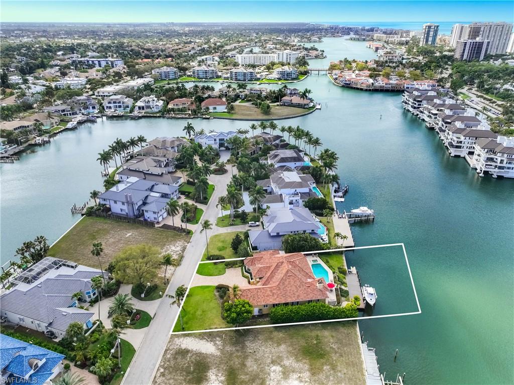 Tucked away on a quiet peninsula street that ends in a cul-de-sac, this elegant bayfront residence captures sweeping western views and breathtaking sunsets over the water, offering a front-row seat to Naples’ coveted waterfront lifestyle. Inspired by European design, the home blends timeless architecture with light-filled interiors, where expansive windows and glass doors frame tranquil bay views throughout the main living areas.
The open-concept living spaces flow seamlessly to the outdoor living area, creating the perfect setting for both everyday living and entertaining. A resort-style pool and spa overlook the bay, surrounded by generous terraces designed for relaxed coastal living. Three retractable remote-controlled awnings provide shade and comfort over the poolside seating areas, allowing you to enjoy the waterfront setting throughout the day.
Boating enthusiasts will appreciate the private dock with direct Gulf access, offering effortless days on the water. Positioned at a high elevation with no history of flooding, the property offers both beauty and peace of mind. Additional features include a 120-gallon propane tank, a whole-home Savant sound system, and thoughtfully designed outdoor spaces that embrace the natural surroundings.
Residents of Park Shore are eligible for membership to the private Park Shore Beach Park, which offers beach access, parking, restrooms, and a beautiful stretch of white-sand Gulf beach exclusively for members.
Ideally located just minutes from Naples’ world-class beaches, fine dining, and shopping, this exceptional bayfront home presents a rare opportunity to experience the best of luxury waterfront living in Naples.