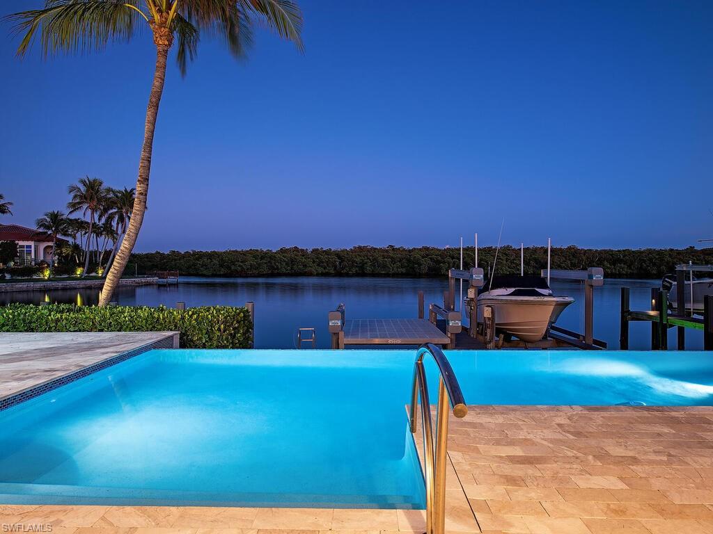 Prepare to be mesmerized by the breathtaking wide-water views of Haldeman Creek, complemented by the stunning natural beauty of the surrounding mangroves. Crafted by Foresite Homes and designed by the renowned architectural firm Stofft Cooney, this exquisite coastal-style residence boasts over 4,600 square feet of luxurious interior living space. Thoughtfully designed to maximize the panoramic water views, the great room kitchen, breakfast nook, and master bedroom all provide a serene backdrop of nature's finest. The expansive first-floor master suite is a true retreat, featuring an elegant bathroom with dual vanities, a sophisticated make-up desk, a spacious dressing room, and an enormous walk-in closet. Upstairs, you'll find three generously sized bedroom suites, each offering stunning vistas and access to expansive covered balconies with a motorized screen. The outdoor living areas are equally impressive, featuring motorized screens and an outdoor kitchen, perfect for entertaining next to the infinity-edge pool and spa. A private dock with a Bendpak li(9,000 lb.) boat lift, flat 16,000 lb and 10,000 lb lift await your watercraft, offering seamless access to the beautiful waterways. Residence is finished with motorized screens for the living room opening and a 40kW generator. This remarkable home embodies the essence of coastal living in the prestigious Royal Harbor community.