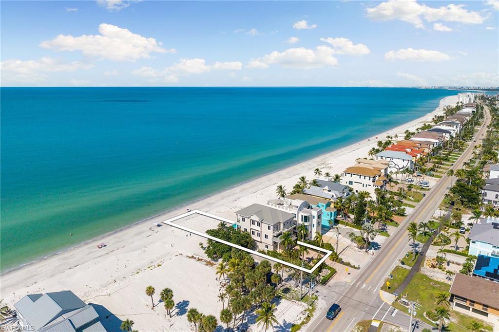 Experience stunning views from this completely designer-updated and extended five-bedroom-plus-den home, directly on the sand of Bonita Beach with RARE ELEVATED POOL DECK! Extensively extended and renovated in 2018 & 2023, the expansive great room features approximately 40 feet of sliding glass doors, providing unparalleled vistas of the Gulf of Mexico and effortless access to outdoor living. The open-plan layout is ideal for entertaining, with the luxurious living room showcasing incredible Gulf views across the sparkling infinity pool and covered outdoor living area. The gourmet kitchen is a chef’s dream, equipped with high-end appliances, beautiful countertops and exquisite designer finishes. Retreat to the opulent main bedroom suite, a sanctuary complete with wide glass sliding doors leading to a private balcony that boasts sweeping beach views. Indulge in the lavish en-suite bath, featuring premium fixtures and finishes, creating an escape at end of the day.  Enjoy the beautiful panoramic gulf views from the outside open balcony. It’s an ideal spot to inspire creativity or simply enjoy peaceful moments. Go outside to revel in the incredible elevated infinity-edge pool at rear of the home, where you can bask in the sun on the extended sun terrace, surrounded by seamless glass railings, all while taking in spectacular sunsets and captivating Gulf views. The outdoor kitchen by the pool is ideal for alfresco dining and entertaining, ensuring every gathering is memorable. This home is designed with exceptional quality and attention to detail, featuring stunning wood flooring throughout, a private elevator, soaring 12-foot ceilings, poured concrete construction, and impact-resistant doors and windows. With a spacious five-car garage, this coastal paradise has it all.