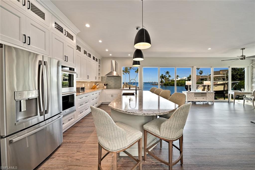 Spectacular bay views from this gorgeous home that exudes casual elegance. Sit back and enjoy the dolphins, pelicans and boaters from this open floor plan. For boating enthusiasts, it doesn't get any better: Deep water, quick Gulf access, 16,000 lb boat lift, seawall, and long dock with room for a guest boat. Coastal contemporary design with attention to every detail, including a walk-in wine room. Gorgeous kitchen has Cambria countertops, stainless steel appliances and plenty of seating for family and friends. The expansive primary suite is located on the 2nd level to take advantage of the stunning bay views and has a sitting area, screened balcony and beautifully appointed bathroom. The 4th bedroom, with bathroom, is set up as an exceptional office with more water views and built-in cabinetry. There is even a rooftop sundeck. The grounds are meticulous with tropical plantings, heated swimming pool with waterfall, and patio. 1500 Angel Drive is a must-see!