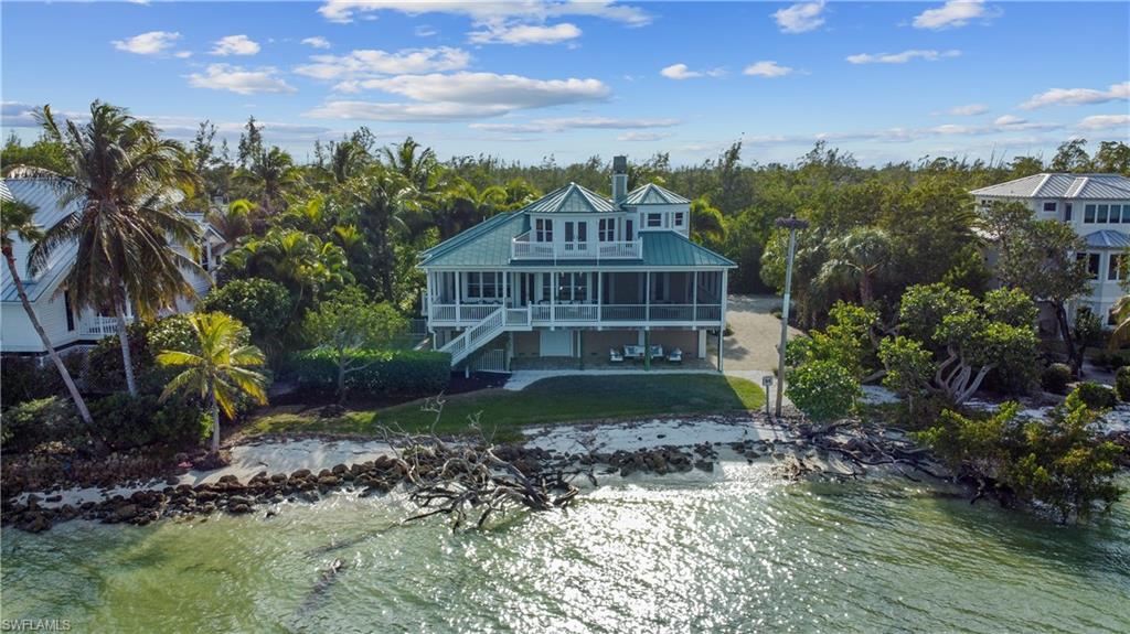 H.15553 - Captivating views of the bay from this bayfront pool home, complete with its own beach!  Enjoy watching the birds and boats go by from open and screened porches on all 3 floors, all accessible by elevator. The main living area has a gourmet kitchen that overlooks the dining and living areas, an expansive island with wine cooler, custom cabinetry, and new stainless appliances. For the cooler evenings, you can curl up by your cozy wood burning fireplace. On the main floor are 2 guest rooms with ensuite baths and another set-up currently as an office. 2 have access to the large bayfront porch. A luxurious master retreat awaits you on the top floor, complete with a separate sitting/office area. Impeccable finishes throughout, including hand-scraped hardwood flooring, coffered ceilings, wainscoting, plantation shutters and impact doors/windows. The lower level has a bonus room that could be a media, bunk, workout, or game room, and a ½ bath and a workshop area along with room for 2 cars.  EZ on and off the island and convenient to bike trails, beaches, restaurants, and shopping from this upscale home that sits across from a preservation area. A fantastic home for entertaining!