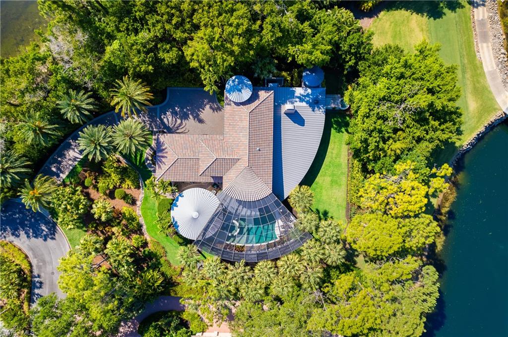Introducing a masterpiece of architectural ingenuity harmonizing seamlessly with the splendor of its natural surroundings. This ‘radial designed home’ features a 180-degree curved veranda, embracing panoramic vistas of the Pine golf course fairway, serene lake, majestic pines, and stunning landscaping. Inside, an open floor plan fosters fluidity and expansive space allowing you to optimize the use of space to suit various lifestyle preferences.  The home boasts just over 5000 sq ft, with 3 bedrooms plus den with elevator. A cozy library provides a serene retreat for book enthusiasts, while a flexible space offers boundless opportunities for customization and personalization, whether as a home office, fitness area, or creative studio.The main living area gracefully transitions into a generously proportioned lanai, featuring a gorgeous pool and spa. Discover a secluded retreat, featuring a private covered area adorned with a tranquil fountain and inviting sitting area.  The property boasts a detached guest house, elegantly designed in a circular style, resembling a charming casita.Grey Oaks community offers premier recreational facilities, including a sprawling 30,000 square foot wellness center, three world-class golf courses, tennis and pickleball courts, bocce, two clubhouses, and a resort-style pool. Beyond its exceptional amenities, Grey Oaks boasts a reputation for unparalleled service, delivering a first-class living experience.