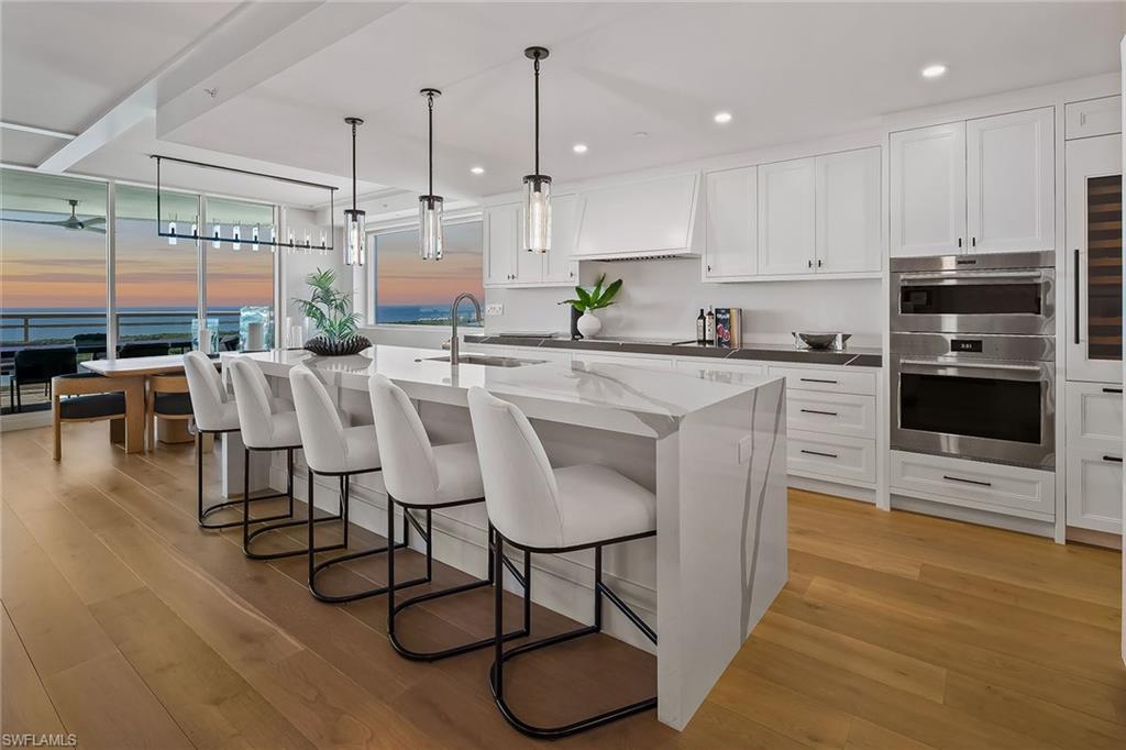 Wake up to breathtaking Gulf and bay views from this stunning, pet-friendly 3,722-square-foot, 22nd-floor luxury residence in Tower 300 at Kalea Bay, one of Naples, Florida’s prestigious resort communities. This newer-construction, furnished residence offers an exceptional coastal lifestyle with three bedrooms plus a den (optional fourth bedroom), three-and-a-half baths, and refined interiors by RH design. The open-concept living space flows seamlessly to a west-facing wraparound terrace with glass railings, showcasing panoramic sunsets, Gulf and Intracoastal boating views, sugar-white beaches, the sparkling skyline of North Naples, and golf views of Kinsale Golf Club just across the street. The chef's kitchen features Wolf and Sub-Zero appliances, quartz countertops, oversized island, wine cooler, refrigerator and freezer drawers, and a butler’s pantry. The primary suite is a private retreat with water views, spa-style bath, dual vanities, soaking tub, walk-in shower, bidet and a generous built-in closet. All bedrooms are en-suite with built-in closets, and the main living area features pocketing impact doors that open directly to the water views. Additional highlights include a large laundry room with built-in office, hardwood floors and custom millwork throughout, soaring ceilings, designer lighting, impact-resistant glass, solid-wood doors, private elevator entry and accordion storm shutters on the lanai. Residents enjoy five-star tower amenities including rooftop pool and barbecue, fitness center, party room and catering kitchen, along with full membership at The Club at Kalea Bay, featuring three resort-style pools, two poolside tiki huts, two on-site restaurants, a $14 million state-of-the-art fitness and wellness center, tennis, pickleball, bocce, 12 exclusive guest cottages, dog park, beauty salon, kayak and paddleboard launch, business center, kids and teens centers, and a vibrant calendar of social events. The optional Beach Club offers indoor and outdoor beachfront dining, along with full chair, umbrella, towel, and food-and-beverage service on the beach. Guard-gated with 24/7 security and two assigned garage spaces on upper lobby level, this residence represents the pinnacle of luxury coastal living in Naples.