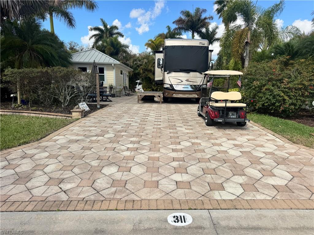 Looking for a large coach house in a prime location—close to the River Clubhouse, with no neighbors directly behind you, offering privacy, space, and a welcoming setting for your fur friends? You’ve just found it at lot 311. As you pull into this back-in lot, you immediately feel the sense of space and seclusion. Lush landscaping frames the property, and with no rear neighbors, your outdoor living feels open, peaceful, and wonderfully private. It’s the kind of setting where mornings start slowly with coffee in the sunshine and evenings end under a sky full of stars. Step inside the coach house and you’ll discover a layout designed for real living. The kitchen is a dream for the gourmet at heart, plenty of space to prep, cook, and entertain with ease. There’s a generous pantry closet, with the washer and dryer tucked neatly inside for convenience without sacrificing style. The bathroom features a full shower, and the bonus room offers flexibility for whatever suits your lifestyle—home office, hobby room or project space. It’s a coach house with options, and that’s what makes it special. Outside, imagine sun-soaked afternoons lounging with friends, evening cocktails with neighbors, and plenty of room for your four-legged companions to feel right at home. This lot was designed for both relaxation and connection. And the location? Truly ideal. Just a short stroll to the River Clubhouse, making it effortless to join in the fun. Wander over the charming footbridge to the main pool area where daytime energy fills the air and take a refreshing dip whenever the mood strikes. You’re close to everything, yet tucked into your own private retreat. Life at RiverBend Motorcoach Resort means you’re never short on options. With three clubhouses, you can spend afternoons poolside at the cabana bar, take a refreshing swim in the resort-style pool, unwind in the hot tubs, or enjoy riverside evenings with live music and themed dinners. Prefer to stay active? Join trivia night, gather for bocce, try Zumba or line dancing, or test your poker face at Texas Hold-Em. The lifestyle is vibrant, welcoming, and entirely up to you, be as social or as relaxed as you’d like. This isn’t just a lot. It’s a lifestyle upgrade. Pull in. Plug in. Let the fun begin. There is a golf cart that can be negotiated with purchase of property. Note it is not the golf cart in pictures.