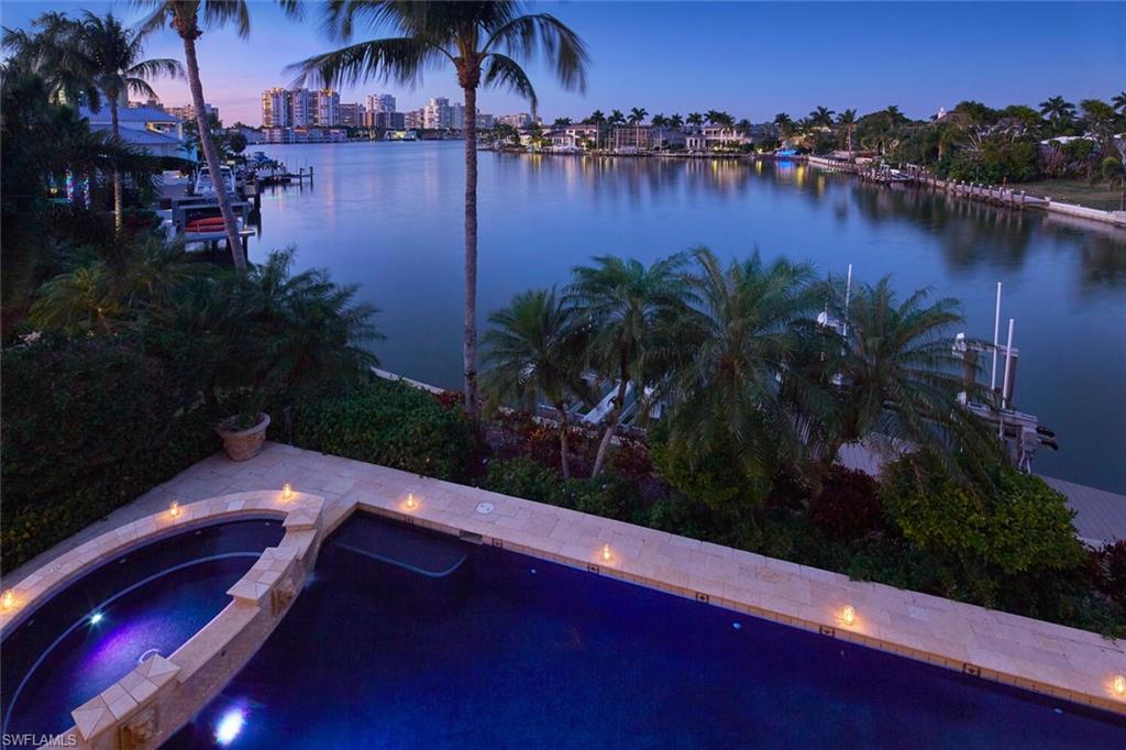 Nestled on two lots along the serene bayfront in the prestigious Moorings neighborhood, this luxurious home stands as a testament to coastal elegance and wide water views. Upon entering the residence, guests are greeted by the graceful expanse of the foyer leading to the formal living and dining areas complete with a charming fireplace and a wall of windows framing the pool and water beyond. The five en-suite bedroom layout, thoughtfully designed, ensures ample space for both comfort and privacy, offering panoramic views of the bay or the meticulously landscaped grounds. The heart of the home lies in its gourmet kitchen, adorned with state-of-the-art appliances and a walk in pantry. Entertaining is a delight in the expansive living areas, where large windows frame breathtaking scenes of the bay, creating a seamless connection between indoors and the picturesque outdoors. An exceptional game room with a magnificent bar and wine storage add to the endless entertaining venues. The property also boasts a five-car garage, catering to the automotive enthusiast or those with an extensive collection. The beautifully manicured grounds surround a plethora of outdoor amenities, including a poolside oasis perfect for relaxation. The private boat dock extends a personal invitation to explore the waterways at a moment's notice, making it a haven for water enthusiasts. As the sun sets over the bay, the home's outdoor living spaces come alive, offering a perfect setting for alfresco dining or evening soirees. The harmonious blend of architectural sophistication, natural beauty, and modern conveniences make this bayfront estate an unparalleled retreat for those seeking the epitome of coastal living.