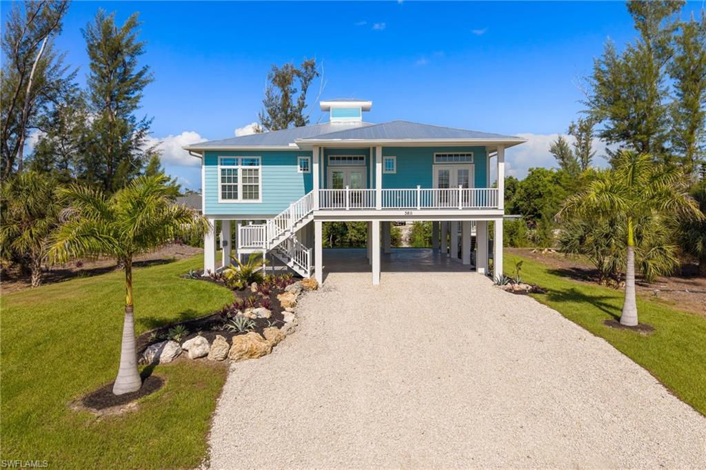 Experience the Essence of Island Living!  Welcome to this exceptional stilt home, perfectly situated on an oversized homesite with an impressive 100 feet of freshwater canal frontage. Thoughtfully designed to embrace the island lifestyle, this beautifully appointed residence offers 3 bedrooms, 3 full bathrooms, impact-resistant windows and doors, durable James Hardie® fiber cement siding, and a long-lasting metal roof, providing both style and peace of mind.  An expansive wraparound deck extends across both the front and rear of the home, creating the perfect setting to relax, entertain, and enjoy peaceful water views from every angle. Inside, the bright and airy open-concept great room is filled with natural light and showcases soaring volume ceilings, a striking tray ceiling in the living area, and beautiful laminate flooring throughout.  The gourmet kitchen is designed to impress, featuring elegant gray shaker cabinetry, crisp white subway tile backsplash, stainless steel appliances, quartz countertops, a spacious center island with pendant lighting, and a dining area overlooking the tranquil canal—an ideal space for everyday living and effortless entertaining.  The spacious primary suite serves as a private retreat, complete with a tray ceiling, walk-in closet, and sliding glass doors leading directly to the rear deck, where you can enjoy your morning coffee while taking in the serene waterfront setting. The luxurious en-suite bathroom features a large tiled walk-in shower and a dual-sink vanity.  Guests will appreciate the privacy of the second bedroom, which includes its own en-suite bathroom. The versatile third bedroom, highlighted by French doors opening to the front deck, is perfect for family, visitors, or a home office. A third full bathroom and a separate laundry room add convenience and functionality.  The ground level offers abundant covered parking on a spacious concrete pad, providing plenty of room for vehicles, recreational equipment, and additional storage.  Whether you're searching for a peaceful island retreat, a full-time residence, or an exceptional investment opportunity, this remarkable waterfront home offers the perfect blend of coastal charm, modern comfort, and quality construction.  Schedule your private showing today and discover the relaxed beauty of island living!