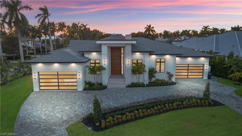 Designed by JMDG Architecture, this brand new Moorings residence draws direct influence from modern Italian homes. Porcelanosa is used for flooring throughout all interior living spaces, wall finishes and showers in every bathroom, and the exterior kitchen backsplash. All cabinetry in the home, including the kitchen and custom closet systems, was designed, built, and imported from Italy by Copatlife. There are no baseboards, no crown molding, no door frames, and no traditional door hardware. Interior doors are Italian-made pivot doors by Ghizzi & Benatti, built directly into the walls with integrated hand-slit pulls, while the entry is highlighted by a 16-foot wood front door. The kitchen features Gaggenau appliances, including integrated refrigerator and freezer, two full ovens plus a steam oven, dual dishwashers, onyx countertops, and a flush cooktop with a built-in pop-up downdraft ventilation system. The home is equipped with a full Lutron lighting system, along with a Pentair whole-home water filtration system, a 1,000 gallon propane tank, Andersen sliding glass doors and impact windows, and expansive indoor-outdoor living with a custom pool, spa, and outdoor kitchen.