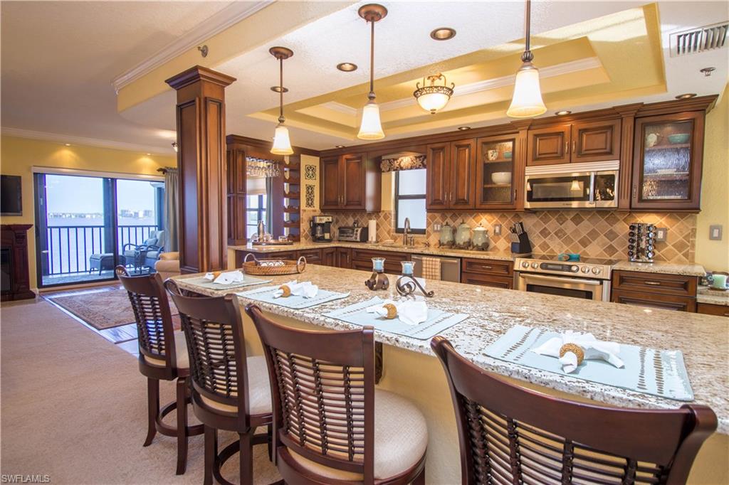 WOW! Walk through the door of this 9th floor condo and be awestruck by the gorgeous kitchen and the endless water views! This three bedroom/2 bath, END-UNIT is completely move-in ready and beckons you to come in and relax. The kitchen boasts stainless Bosch appliances, custom soft-close cabinets, a pantry with pullout shelves, granite countertops, and a built-in desk. Enjoy the luxury of a deep, jetted tub in the guest bathroom, and dual sinks and a frameless shower door in the master bathroom. Many added luxuries such as TWO screened balconies, electric hurricane shutters, impact resistant windows, TWO assigned carports, crown molding, upgraded lighting, an electric fireplace, generous closets (including an exterior storage closet), and a water softener. Walk to several great restaurants or to Downtown Fort Myers to enjoy the nightlife. Seasonally, you can take the FREE Downtown Trolley to restaurants or area attractions like the Edison Ford Estates. Publix is only a block away! TURNKEY with tasteful furnishings and everything you need to make it a home from day one; this condo is waiting for you! Be sure to check out the virtual tour to walk through the condo right now.