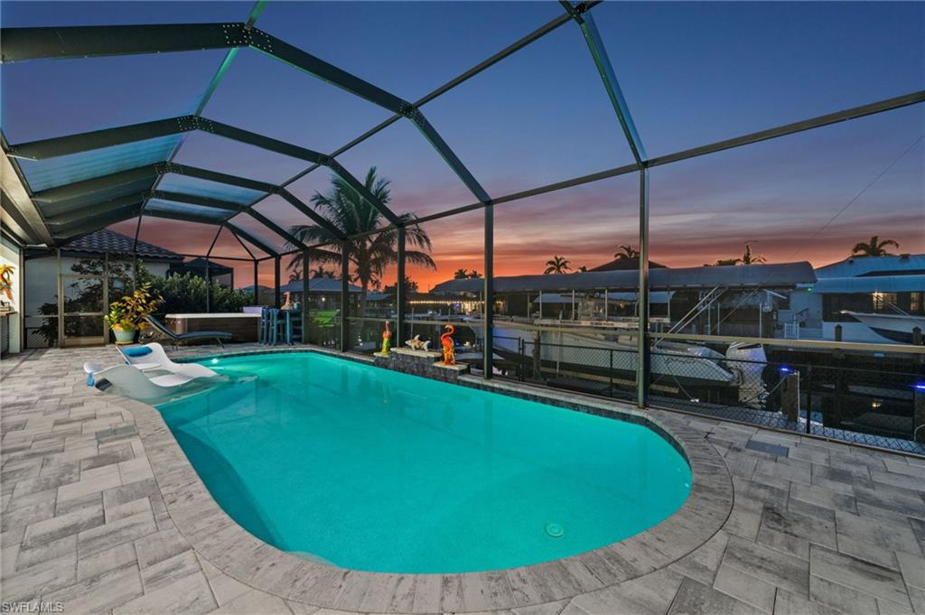 A rare blend of island serenity & modern sophistication, custom-built 2022 Tundra waterfront residence delivers refined coastal living w/ exceptional peace of mind. Assumable flood insurance under $600/year. Step inside to a thoughtfully designed first-floor living space created for both everyday comfort & effortless entertaining. The open great-room concept offers distinct yet connected living areas ideal for hosting guests while soaring vaulted ceilings allow natural light to flood the home. Zero-corner pocketing sliders fully open the great room to the lanai, seamlessly blending indoor & outdoor living. At the heart of the home is a showstopping chef’s kitchen designed to impress, featuring upgraded JennAir appliances, induction range, oversized refrigerator, double oven, &  statement vent hood. Granite countertops, custom wood cabinetry adorned w/ crown molding & under-cabinet lighting, a spacious walk-in pantry, & dedicated coffee/bar area complete this entertainer’s dream kitchen. The spacious primary suite is a private retreat offering 2 walk-in closets, 2 separate vanities, & a spa-inspired bath w/ a generous two-person walk-in shower featuring multiple shower heads & plumbing in place for a future soaking tub. Private sliding glass doors provide direct access to the lanai, creating a seamless connection to the outdoor living space. The first level continues to impress w/ 2 guest bedrooms, one serving as a true en-suite w/ walk-in closet, while the second has its own full bath that also functions as a convenient pool bath. A dedicated den on this level provides flexible living space & could easily be converted into an additional bedroom. Completing this floor is a spacious laundry room featuring ample cabinetry, overhead storage, generous countertop space & abundant additional storage. Outdoor living is elevated to resort style on the cypress-lined lanai, featuring a heated pool w/ sun shelf and watrerfall, a standalone six-person hot tub & a fully equipped outdoor kitchen w/ eat-at bar, beverage refrigerator, ice maker, built-in grill, sink & a designated area wired w/ 220-amp electric for a future stove. Upstairs, a private second-floor guest suite offers exceptional versatility. Currently used as a theater room, this space includes a private kitchenette, full bath & flexible layout—ideal for extended stays or a secluded guest retreat. Two screened balconies, both finished with cypress ceilings, provide peaceful sunrise views on one side & spectacular sunset views on the other. Boating and fishing enthusiasts will appreciate the composite dock w/ captain’s walk, fish-cleaning station, and two boat lifts—one 13K covered & one 10K —offering effortless access to open water. Additional features include an extended 800+ sq ft air-conditioned three-car garage with epoxy floors, 42" SS sink, dual A/C systems, instant hot water heater, a 400-amp generator-wired service, fenced backyard w/  dog run & so much more see attached list of features.