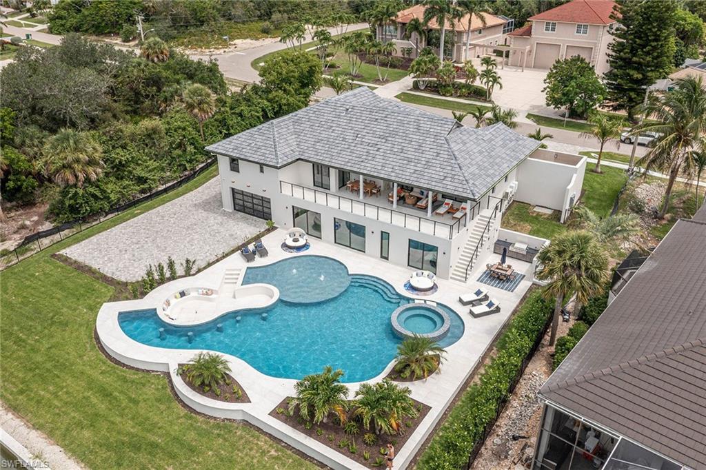 Stunning, fully updated in 2026 waterfront retreat offering luxury living and exceptional indoor-outdoor entertainment. This beautiful home features abundant natural light, custom cabinetry throughout, and a fully appliance gourmet kitchen with a large island that opens to the great room with a striking fireplace feature wall. A spacious dining area flows seamlessly into the kitchen and dining space. The main level includes four bedrooms, one with private exterior access. A luxurious primary suite complete with a private outdoor shower. Enjoy the convenience of upstairs and downstairs laundry rooms. The walkout lower level is designed for entertaining, featuring two additional bedroom suites, a custom movie room with TV, popcorn station, refrigerator and built-in cabinetry, plus a full summer kitchen with island and dining space, all opening to beautiful pool and waterfront views. Additional gathering space includes serving cabinetry and towel storage. Go outside to a resort-style setting with a spectacular pool, large spa, fire bowl seating area, fountains, sunning space and expansive seating areas. An outdoor dining area with built-in grill and cabinetry enhances the experience, along with additional guest parking. The oversized air-conditioned garage downstairs showcases a custom floor, LED lighting and glass doors, and opens to a unique cigar/sports lounge with bar cabinetry, refrigerators and a half bath. The property is fully landscaped with a gated rear entry for added parking and garage access. In addition, there is an upstairs air-conditioned two-car garage that can also accommodate car lifts. Ideally located for boating enthusiasts with easy access to open water. With new mechanicals, roof, pool and interior finishes throughout, this home offers a blend of luxury, comfort and lifestyle.