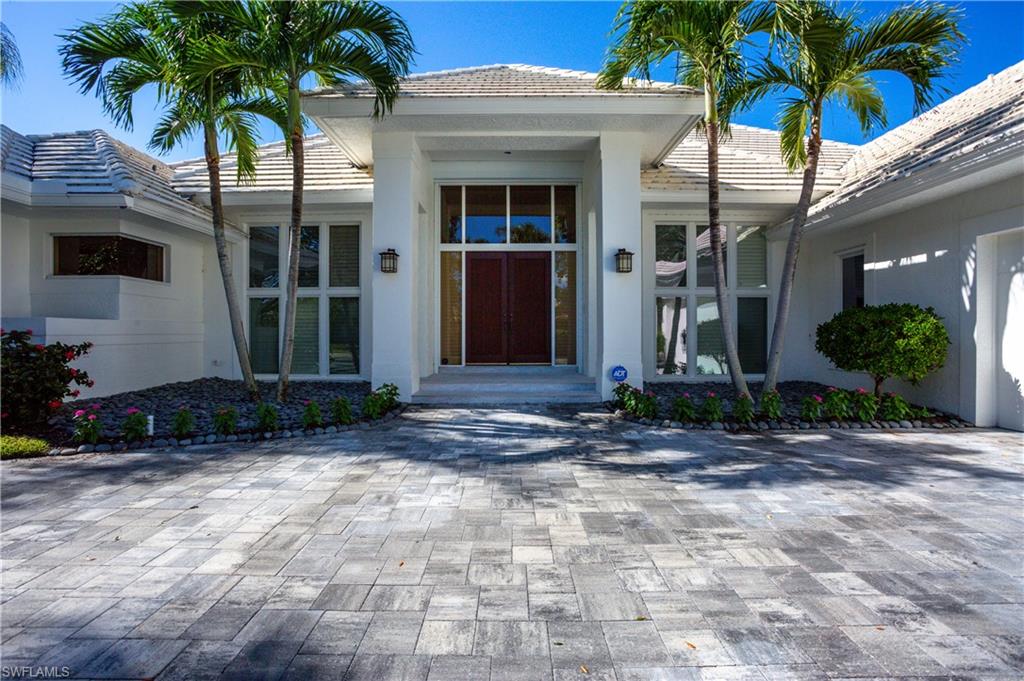 Stunning panoramic golf course and lake views abound. Light and bright best describe this lovely home. Interior features welcome you with beautiful wood flooring, statement fireplace, volume custom wood ceiling, updated kitchen and baths, spacious private primary suite, two en suite bedrooms and office could be used as a fourth bedroom. Living and Family rooms overlook the expansive lanai with large pool and spa that enjoys one of the best views in Pelican Bay. Perfect for outdoor living and entertaining. Exterior features include lush tropical landscape, circular paved drive and a new roof 2023. Pelican Bay is an amenity rich community. Residents enjoy three miles of beach with two private beachfront pavilions with restaurants, miles of walking paths, kayaks and canoes for resident use, tennis, pickle ball is coming soon and state of the art fitness center with spa. The Golf Club at Pelican Bay offers private membership. Centrally located between The Ritz Carlton Beach Resort and upscale Waterside Shops and Restaurants. This is the ultimate in Florida living.