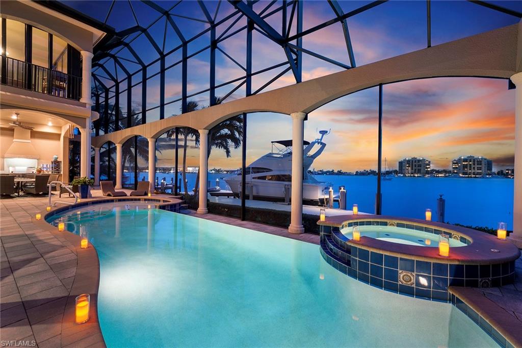 Sunsets, dolphins, birds, cruising boats all on the Marco River. Imagine waking up daily to the panoramic views of endless beauty from this luxurious custom crafted home by DIVCO. Turnkey furnished, over 5,600 SF under air,  welcoming double door entry, voluminous great room, coffered and tray ceilings all open to the lanai leading to the outdoor kitchen and fireplace, custom swimming pool and spa with sun shelf, infinity edge, panoramic stucco framed screened enclosure and paver deck. The 30,000-pound lift, 2005 seawall and oversized dock provide for a boater's dream. The gourmet kitchen has beautiful cabinets, granite counters, tumbled marble, a gas range, KitchenAid appliances and a built-in Miele coffee maker. A very special feature is the Wine Room with two wine refrigerators. Master Suite offers Lanai Access, Sitting Area, His/Hers CA Walk-In Closets, His/Hers Vanities, Jetted Tub/Walk-In Shower. Ascend the Staircase to Media Room with Movie Screen/Wet Bar, Game Room with Billiards & WALLS OF IMPACT SLIDERS. 3 Car Garage, Audio System, 3 AC Zones, 25KW Generator & Fine Furnishings Complete the 7,552 SF Timeless Beauty!