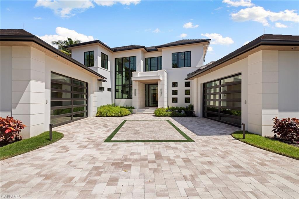 Open the glass pivot front door and step inside this timeless architectural masterpiece in Royal Harbor, masterfully designed by award-winning local architect Stofft Cooney. A dramatic double-height feature window, backlit Cristallo Quartzite entry, and floating open staircase with glass railings make an immediate statement, setting the tone for a home that blends clean contemporary design with warm, livable luxury.

As you move into the main living space, the home opens beautifully to the water, with expansive walls of glass framing the bay and drawing your eye straight to the outdoor living areas beyond. Large-format porcelain tile and light oak flooring run throughout, while a built-in vapor fireplace with a marble surround and wood feature wall anchors the living room with both texture and sophistication.

The kitchen is as striking as it is functional, finished with Taj Mal countertops, top-of-the-line Wolf appliances, and a separate service kitchen designed for effortless entertaining. Every space has been thoughtfully curated for both everyday comfort and large-scale hosting.

The residence offers 4 bedrooms plus a study or optional 5th bedroom, 6 full baths, and 1 half bath, along with 2 primary suites and a 4-car air-conditioned garage. The first-floor primary suite is a true retreat, positioned to capture stunning bay views and paired with a spa-like bath that feels private and serene.

Whether taking the elevator or the statement staircase upstairs, the home continues to unfold with beautifully appointed guest accommodations and private spaces, all tied together by a seamless smart-home experience. Lutron lighting and shade control, Control 4 smart automation, automated roll-down privacy shades, a 1,000-gallon propane tank, and whole-house generator all contribute to the home’s exceptional ease and functionality.

Outside, the lifestyle is every bit as impressive. The covered outdoor living area is designed as an extension of the home, complete with a full summer kitchen, automated roll-down screens and shutters, Marbella limestone accents, and multiple spaces to lounge or entertain. The resort-style pool and large infinity-edge sun shelf overlook the bay, while 100 feet of new seawall and unrestricted boating access make this an ideal waterfront setting.

Set on an oversized 0.40-acre lot with 5,500 square feet under air and more than 7,700 square feet of covered living space, this exceptional residence offers the rare combination of architectural pedigree, modern luxury, and an unbeatable Royal Harbor location just a short walk or bike ride from downtown Naples and its white sand beaches.