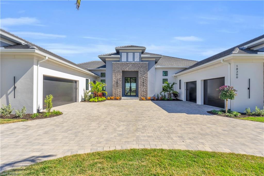 Welcome home to 18300 Blue Eye Loop, a magnificent Stock Custom Home located on a fabulous NE facing waterfront estate lot in Wild Blue, this exceptional residence epitomizes luxury and sophistication, offering an unparalleled living experience with its exquisite design and prime location. Spanning an expansive floor plan, the “Alexandria” model features a spacious 4,699SF of under air living with 4BD+Den/Study, 5BA plus a half bath, bonus room, dining room, great room & epoxied 4-car garage with circular driveway. Every detail of this residence is meticulously crafted with the utmost high-end finishes, designed and comes FULLY FURNISHED by the renowned Clive Daniel Home, ensuring a seamless blend of elegance and comfort. The color palette features cool whites & creams, rich brown wood tones, dusky charcoals, and deep teals throughout, accented by gold hardware and artistic lighting. Anderson 400 impact windows, impact doors, 2 tankless hot water heaters, spray foam insulation, solid core modern slab interior doors, wide plank wood flooring, custom built-ins, beam details, home automation, security system are just a few features to mention. The spacious open chef’s kitchen includes natural gas stove, large seating Quartz island, Quartz countertops & full height backsplash, Sub-Zero & Wolf appliances. The adjacent dining and living areas offer stunning views of the waterfront, creating a serene and inviting atmosphere. The luxurious master suite is a private sanctuary, upon entry you are greeted with a morning bar & sink, under counter refrigeration & open shelving, tray ceilings, headboard feature wall, custom master closets & an en-suite with large walk-in shower, separate water closets, free standing tub & dual vanities. The outdoor living space is an entertainer's paradise. The saltwater pool with a spa and sun shelf invites you to relax and enjoy the Florida sunshine. The outdoor kitchen and tile-clad fireplace area are perfect for hosting gatherings & creating unforgettable memories with family and friends. Stucco and resin beams at outdoor living ceiling also featured.  Residents of Wildblue enjoy a wealth of resort style amenities featuring over 800 acres of freshwater lake, 8 pickleball courts, exercise room, lap pool, spa, clubhouse, tennis, spa, nail salon, kayak & boat launch, walking trails, outdoor grille, bar & much more! With no expense being spared, this exquisite residence represents a rare opportunity to experience the best that Southwest Florida has to offer. The oversized waterfront estate lot offers stunning views and a tranquil setting, making this residence a true oasis. Experience the pinnacle of luxury living at 18300 Blue Eye Loop, where every detail is designed to offer a lifestyle of unparalleled elegance, comfort, and exclusivity.