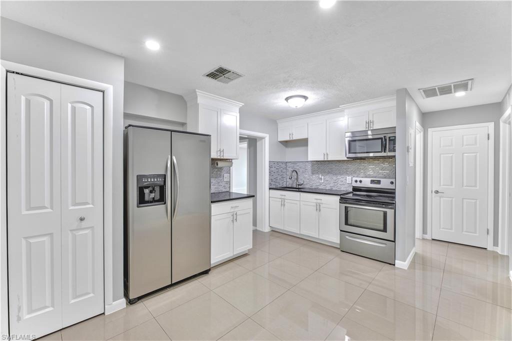 Welcome home to this MAGNIFICENTLY REMODELED 4 bed 1 1/2 bath 6ft PRIVACY fenced corner Villa with CITY WATER & SEWER. It has been freshly painted & spotlights a (2024)HVAC system, new TANKLESS water heater, IMPACT windows & doors, and admirable QUARTZ countertops & shaker cabinets with a glass tiled backsplash. It highlights enticing WOOD PLANK & rectified porcelain tile flooring, newer STAINLESS STEEL appliances, walk in closets, spacious bedrooms, epoxy flooring, (2023)Mini split, new fixtures, and a (2014)Dimensional shingle roof. It also features recessed led lighting, new window treatments, a pantry, new vanity, additional storage space, and an oversized driveway with plenty of room for parking. This property is conveniently located just minutes from all major amenities nestled away on a loop with a quick commute to Fort Myers. Schedule your showing today!