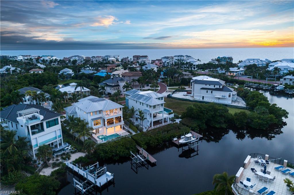 SKIP THE WAITLIST! THE CLUB AT BAREFOOT BEACH MEMBERSHIP AVAILABLE WITH THIS HOME, SPECIFICALLY! A RARE & UNIQUE OPPORTUNITY! Luxury 2018-built coastal contemporary home in the exclusive double-gated Southport on the Bay, within North Naples’ premier “Barefoot Beach” community. A beach and boater’s paradise, this estate offers deeded beach access just a short walk away and direct Gulf-access only 10 minutes from your private boat dock and lift (featuring a new panel and mechanics). Relax and entertain outdoors with a pool and spa surrounded by new travertine decking and plenty of lounging space, plus an upper-level screened lanai with summer kitchen —complete with a new gas grill and refrigerator—ideal for dining al fresco. Brimming with natural light, this home offers an open floor plan with 4 bedrooms plus den/office (all bedrooms with en suite baths), soaring 12 ft ceilings, wide-plank hardwood floors, and tongue-and-groove ceilings with custom wood beams. The chef’s kitchen boasts Miele appliances, a spacious butler’s pantry, and stunning custom cabinetry with granite and quartz counters. The primary suite is a private retreat, complete with French doors opening to an open-air balcony overlooking the bay, a wet bar with wine fridge, a large walk-in closet with custom built-ins, and a spa-like bath with dual vanities, soaking tub, and a spacious rainfall shower. Additional highlights include a brand-new tankless water heater, new audio/visual system and tower, PGT impact glass windows and sliders rated for 170 mph, over 400 sq ft of ground-floor flex space, private elevator, and freshly painted exterior. Optional membership to the exclusive "Club at Barefoot" provides access to tennis, two restaurants, beachside food and beverage service, and more. Conveniently located near fine dining, RSW Airport, Mercato, and Waterside Shops, and just 15 miles from the renowned Fifth Avenue in Naples, this home is a true gem in the heart of Barefoot Beach.