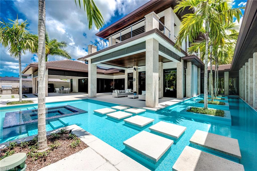 A profound connection to natural surroundings and elements of water define this custom home sited in one of Estuary’s most desirable enclaves. With lake, preserve, and golf course views, the five-bedroom estate exhibits an awe-inspiring gallery of coquina stone columns, deep-hued woodwork and a mesmerizing pool with integrated spa and water feature. Blending elegance with a modern flair the smart-home features 8,549sf of inviting interiors with limestone and wood flooring throughout the main areas, concealed motorized blinds, and imported custom cabinetry coupled with quartzite counter and state-of-the-art appliances. Partitioned in its own wing, the study and a gallery of glass walls adorned with vibrant blue hues lead you to the master suite and private veranda. The second level offers a spacious retreat for family and guests with three bedrooms and a spacious lounge area with covered terrace. The outdoor spaces evoke resort-style living with multiple covered lanai spaces, summer kitchen, spa-inspired pool bath, and heated salt water pool. A dynamic setting with the best in recreational activities complete this exceptionally stylish home.