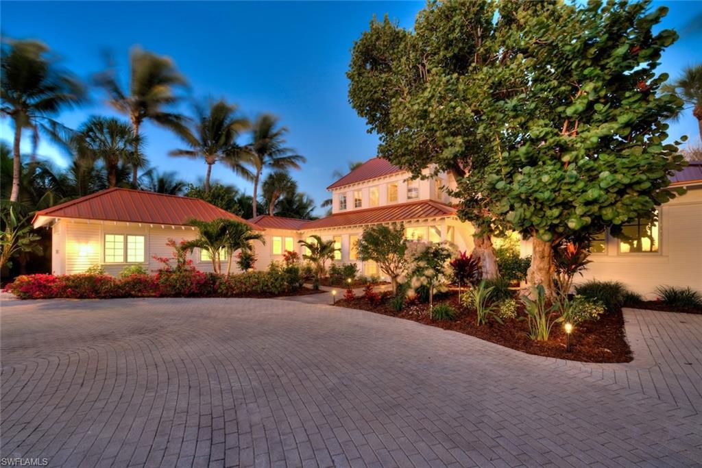 Far-A Way. Long admired as an iconic Captiva residence, this exceptional waterfront estate occupies a coveted position along the Platinum Coast, where timeless island architecture meets refined coastal living. Stretching from the Gulf to the Bay you can have it all! Resting on a high beach ridge with 10 ft of elevation and expertly landscaped by R.S. Walsh, the grounds feature vivid plantings and exceptional specimen trees sourced from around the globe, along with meandering paths beautifully framing the home. Inside, an expansive great room is framed by a dramatic wall of French doors that capture serene water views and flood the space with natural light. The ceilings are  highlighted by exposed white beams and shiplap detailing create an atmosphere of refined coastal elegance, complemented by solid hardwood oak floors that ground the airy scale of the room. Designed for effortless entertaining, the open layout flows seamlessly to the pool and terrace beyond, blurring the boundaries between indoor and outdoor living. Sculptural wood-blade ceiling fans and crisp architectural millwork complete this exceptional island retreat—where craftsmanship, light, and lifestyle converge in perfect harmony. Chef's will admire the open and large finely appointed kitchen. The guest rooms are located on the main level along with the library, office and utility room. A striking lap pool runs elegantly alongside a covered patio, creating a resort-caliber outdoor experience designed for both relaxation and entertaining. At sunrise and sunset, the setting becomes truly breathtaking. Golden light washes across the residence as sweeping views extend over calm bay waters to the shimmering Gulf beyond. A private pier stretches gracefully into the water, inviting boating and sunset cruises, while layered tropical foliage frames the scene with natural elegance. As the sun slips below the horizon, the sky is painted in soft shades of amber, coral, and lavender—gentle coastal breezes stirring the palms and reinforcing the timeless romance of bayfront living paired with spectacular Gulf sunsets.