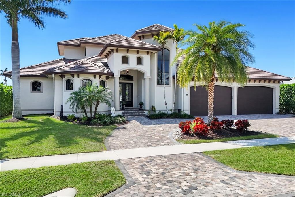 Sun, Sun, Sun! Sought after Southwest Exposure Luxury Waterfront Property. Experience refined coastal living in this stunning 2019 built home with 115 feet of water frontage, providing all-day sunshine on your pool, breathtaking sunset views, a highly coveted 4 car garage, and effortless boating with quick direct access. This impressive two-story residence offers 5 bedrooms plus a private office, 5 full baths, and 2 half baths, with every bedroom featuring its own en-suite bath for exceptional comfort and privacy. A grand foyer welcomes you into a beautifully designed interior highlighted by high-volume ceilings, tray and coffered ceilings, crown molding, elegant baseboards, and solid-core doors throughout. At the heart of the home is a spectacular chef's kitchen designed for both entertaining and everyday living. It features custom Amish-built cabinetry, quartz countertops, a massive center island, custom backsplash, walk-in pantry, stainless steel appliances, wine cooler, and a fully equipped wet bar. Expansive cascading sliders seamlessly connect indoor and outdoor living, filling the home with natural light. The spacious first-floor primary suite offers a serene retreat with a sitting area, generous walk-in closets, and a spa-inspired bath featuring double vanities, marble countertops, a soaking tub, and a walk-in shower with dual shower heads. The main level also offers two guest en-suites, a private office/den, powder bath, and laundry room. Upstairs, you'll find two additional guest en-suites and a generous entertainment loft with its own wet bar, opening to a sunset viewing balcony -- the perfect place to unwind while taking in the waterfront setting. Outdoor living is just as exceptional. The resort-style pool and spa, controlled by Aqualink automation, are complemented by an outdoor summer kitchen, brick paver patio, convenient pool bath, and multiple entertaining areas designed to capture the beautiful southwest exposure. Boaters will appreciate the private dock with water and electric, fishing table, dock box, 16,000 lb boat lift, and jet ski platform lift, along with a new seawall installed in 2016. Additional highlights include electric hurricane shutters, new custom window treatments, a circular brick paver driveway, extensive paver walkways, outdoor shower, panoramic lanai screens, and transferable flood insurance policy only approximately $1,200/year! This exceptional waterfront property offers a premier blend of luxury, comfort, sunshine, and boating lifestyle -- all in one remarkable residence.