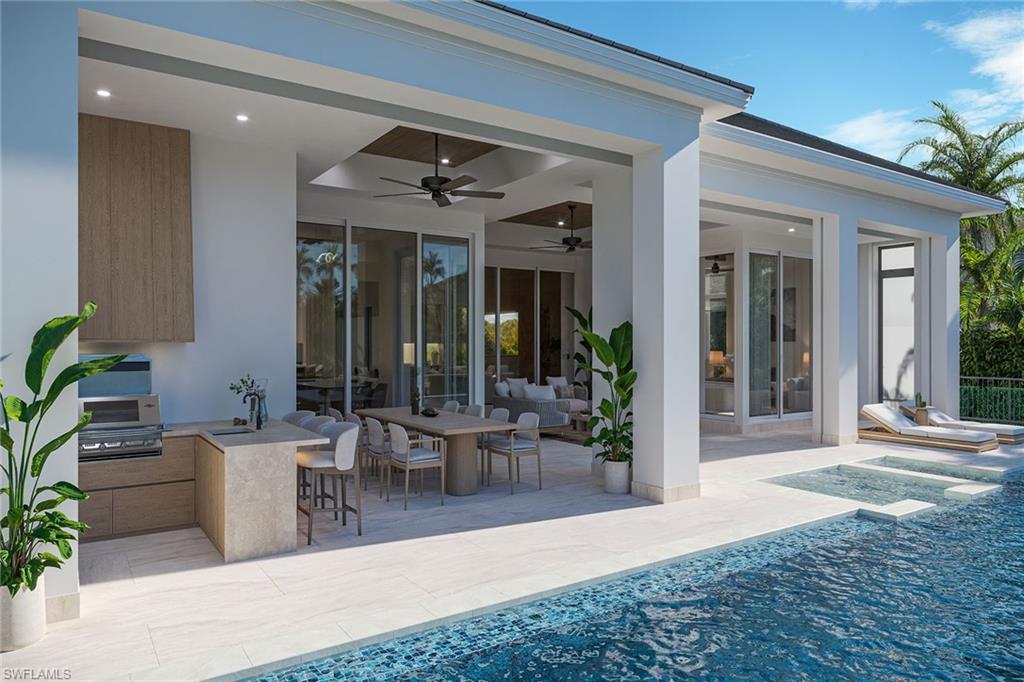 Experience the pinnacle of coastal luxury in this exceptional new waterfront residence, under construction and anticipated for fall 2026 completion, ideally timed to enjoy the holidays and Naples desired winter season in your newly built dream home. Ideally, on a deepwater canal with direct boating access to Naples Bay and the Gulf, this remarkable home offers the ultimate Southwest Florida waterfront lifestyle just moments from Old Naples. This southern-exposure estate places you minutes from the boutiques and fine dining of Fifth Avenue and Third Street, charming waterfront restaurants, renowned art galleries, and the white sands of the area’s world-famous beaches. The best of Naples is at your doorstep. Built to the newest 10-foot base flood elevation standards, this expertly crafted new construction home blends timeless architecture with sophisticated modern luxury. Designed for elegant entertaining and everyday living, the residence offers 3,482 square feet of refined interior living space with five bedrooms plus a den, 5.5 baths and a tall two-car garage with the ability to accommodate lifts for four-car capacity. A custom mahogany door introduces interiors defined by soaring 12-foot ceilings, architectural ceiling details, European wide-plank oak flooring, and expansive walls of glass framing tranquil water views. The dramatic great room showcases a stunning cathedral ceiling, custom built-ins, and a marble-clad vapor fireplace, creating an atmosphere of effortless elegance. At the heart of the home, the kitchen is designed to impress with an oversized island topped in Taj Mahal quartzite and a full suite of premier appliances, including a 48-inch Wolf dual-fuel range, Sub-Zero refrigerator and freezer, Cove dishwasher, and Sub-Zero wine and beverage coolers. The luxurious primary suite offers water views, dual custom closets and a spa-inspired bath adorned with natural stone finishes, a soaking tub and an oversized multi-head shower. Each guest suite features its beautifully appointed en-suite bath with curated designer finishes. Seamless indoor-outdoor living is achieved through nearly 800 square feet of covered lanai space, complete with a summer kitchen, fireplace and water views. The resort-style outdoor setting also features more than 1,200 square feet of deck space, a heated lap pool and spa, a waterfall, natural stone waterline tile and shell stone pavers, all designed to embrace our year-round indoor-outdoor lifestyle. Modern conveniences include a Lutron automation system, wiring for security and motorized shades, remote-controlled drop-down screens and storm shutters, and a whole-house generator. An extraordinary opportunity to own a new waterfront residence with direct boating access near Old Naples, thoughtfully designed, impeccably finished and ready to enjoy before the winter season. Optional memberships available at the nearby Naples Bay Resort to enjoy a fitness club and tennis.