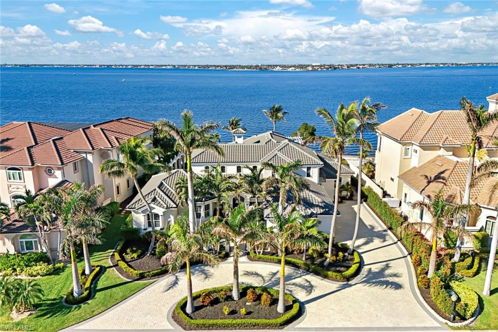 This tremendous home in Gulf Harbour Yacht & Country Club, a prestigious community! Enjoy a 24,000 SQ FT facility offering, gym, yoga, Pilates, spa, indoor golf, 18 HOLE PRIVATE CHAMPIONSHIP GOLF COURSE, 8 (clay) lighted tennis courts & Marina & private island. (memberships available starting at ($52,000.)This remarkable home seamlessly combines luxury living with the serenity of nature, offering an unparalleled lifestyle for its next fortunate owner. Nestled along a tranquil sandy beach, this exceptional riverfront property offers an unmatched blend of luxury, functionality & breath -taking views & design. From the moment you arrive, the water feature, stunning stonework & illuminated landscaping will captivate you, the hurricane-resistant front door & grand marble stone pillars create a striking entryway that sets the tone for this sophisticated home. Inside, the main LR captivates w/ custom marble floors, a double-sided stone & Marble wood-burning fireplace, soaring 25-foot ceilings featuring intricate wood detailing, window surrounding the LV room & foyer to capture perfect natural lighting, French doors open to reveal the pool, spa & your own private beach! A second LV room, equally impressive, provides additional space with 7 sets of French doors leading to your outdoor lifestyle. The immaculate kitchen is a culinary delight complete with double ovens, KitchenAid refrigerator, Bosch DW & an electric cooktop. Thoughtfully designed cabinetry with glass pull-outs &a pantry and pull-out shelving make organization a breeze. 2 sets of French doors lead from kitchen to the outside screened kitchen that offers an Alfresco grille with 2 side burners, granite countertops, a bar, cherry wood ceilings, hurricane shutters, and electronic vinyl shades, creating a year-round outdoor haven. The home boasts a billiard room with hickory hewn floors, a copper sink/wet bar, and a hand-painted mural honoring a painting of golfing legend Bobby Jones. Wine enthusiasts will appreciate the refrigerated wine closet, which can house up to 450 bottles. The upstairs owner's suite serves as a tranquil retreat, featuring 2 sitting areas. a balcony, a screened lanai and a sundeck with unobstructed breathtaking views of the Caloosahatchee River. The lanai is secured with hurricane shutters. The owner’s suite encompasses a full retreat feel with a dressing room, large closet, toilet and bidet. Three additional guest rooms, each w/ private ensuites, 1 on the 2nd floor with private balcony.  The 2 additional guest rooms provide luxurious accommodation for family & friends. Blackout blinds in all bedrooms (except the front room) enhance privacy & comfort. The home’s exterior features include a heated pool and spa. A spacious 3.5-car garage with pull-down stairs offers abundant storage. Modern conveniences like central vacuum, 2 hot water heaters, 80 & 40 gal. 3 AC units (installed between 2015 and 2022) ensure ultimate comfort & efficiency. New roof installed 2020.