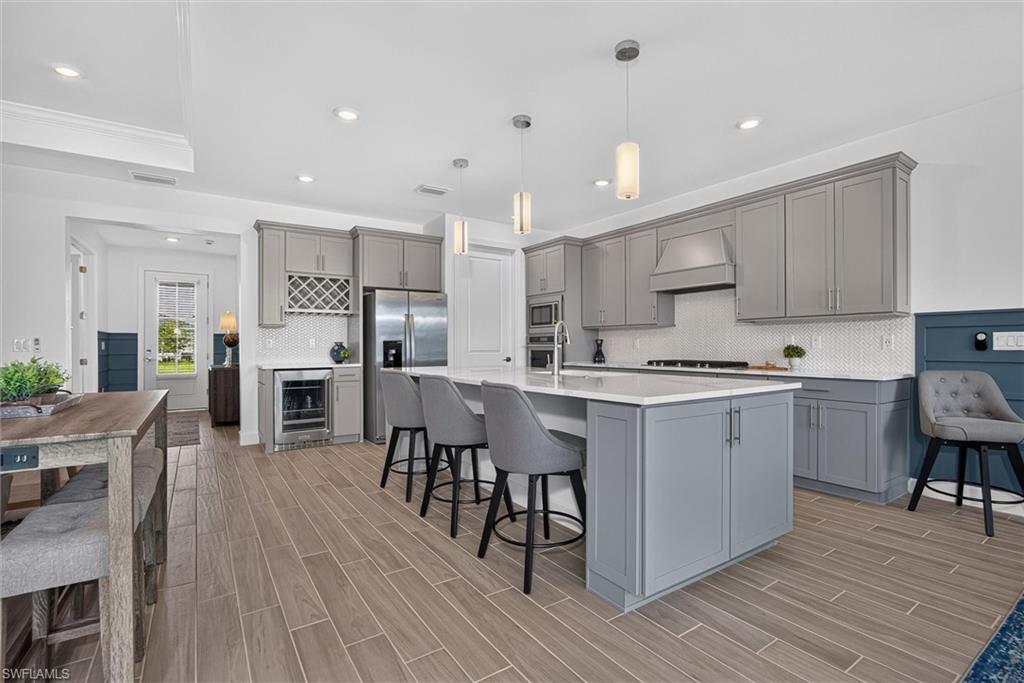 Designer-Furnished Luxury Living with Exceptional Indoor-Outdoor Entertaining. This beautifully appointed 3-bedroom plus den, 3-bath home offers a perfect blend of elegance, comfort, and functionality. From the moment you arrive, you’ll appreciate the wide paver driveway, providing ample parking for family and guests, and the inviting entryway. Thoughtfully designed with custom feature walls, designer wood treatments, and upscale finishes throughout, this home showcases attention to detail in every room. The spacious great room features custom designer wall with a television that remains with the home, creating a warm and welcoming gathering space. The stunning kitchen is truly the heart of the home, featuring quartz countertops, a deep Blanco sink, designer cabinetry, a built-in wine storage area, walk in pantry and an oversized island ideal for entertaining. Whether preparing meals or hosting friends, this kitchen is as beautiful as it is functional. The impressive corner sliding glass doors fully open to the covered lanai, seamlessly blending indoor and outdoor living. This expansive entertaining area provides the perfect setting for relaxing, dining, or enjoying Florida’s year-round sunshine. The owner’s suite is complemented by a truly impressive custom-designed walk-in closet, featuring built-in organization and designer touches that create both beauty and functionality. Thoughtfully crafted to maximize storage while showcasing your wardrobe, this space feels more like a luxury boutique than a traditional closet.  The owners bath has a large walk in shower, dual sinks.  The guest bedrooms each are very private in their own section of the home which provide comfort and style for family and visitors. The guest bath features elegant tile extending to the ceiling, creating a luxurious spa-like feel. A versatile den provides the ideal space for a home office, library, or hobby room. Additional highlights include a spacious walk-in laundry room complete with cabinetry and a utility sink, abundant storage throughout, and a three-car garage. The home is being offered fully furnished, . Beyond the home itself, you’ll enjoy living in Babcock Ranch, America’s first solar-powered town, thoughtfully designed around sustainability, wellness, and community. Conveniently located approximately 30 minutes from both the Punta Gorda Airport and Southwest Florida International Airport in Fort Myers, Babcock Ranch continues to grow and evolve, with a second Publix currently under development, along with an expanding collection of shops, restaurants, and services.  Come and enjoy a vibrant lifestyle filled with community events, concerts, farmers markets, recreational amenities, parks, trails, pickleball courts, sports fields, dog parks, and activities happening year-round. With exciting new additions continually being introduced, there has never been a better time to experience all that Babcock Ranch has to offer.