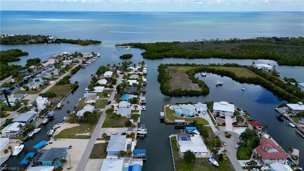 PARADISE FOUND… AND IT’S WEARING FLIP FLOPS. Tucked along the peaceful shores of BOKEELIA on Pine Island, this charming waterfront home captures the laid-back rhythm of Old Florida living—where Gulf breezes drift through swaying palms, boats idle past on the canal and the water is always calling your name. Life here isn’t about rushing anywhere… it’s about fishing at sunrise, boating at sunset and letting the day unfold on island time. Bokeelia sits on the northern tip of Pine Island, a place locals treasure for its quaint fishing-village atmosphere, unspoiled natural beauty and authentic coastal lifestyle far removed from the crowds and high-rises found in more touristy beach towns. Anglers know this area well because the surrounding waters—from Charlotte Harbor to Boca Grande Pass—are among the most productive fishing grounds in Southwest Florida, where tarpon, snook, redfish, trout and grouper have drawn fishermen for generations. AND RIGHT HERE IS WHERE YOUR ISLAND STORY BEGINS… ON A DIRECT ACCESS SALTWATER CANAL JUST MINUTES TO OPEN WATER. No bridges to slow you down—simply idle out to the harbor and the Gulf beyond. At water’s edge the dock features a 10,000 LB BOAT LIFT with canopy plus a convenient fish cleaning station, making it easy to head out for a quick evening cruise or a full day chasing the next big catch. Even better, this is a BOAT AND RV FRIENDLY COMMUNITY with NO HOA—plus it’s PET FRIENDLY AND RENT FRIENDLY too. Inside, the home offers a naturally bright, breezy and cheerful feel with a well-designed split bedroom floorplan. There are THREE BEDROOMS, TWO BATHS AND A TWO-CAR GARAGE with tile and wood flooring throughout—no carpet. The guest suites are generously sized and share a beautifully remodeled guest bathroom completed in 2024. The primary suite enjoys sliding glass doors to the lanai, a walk-in closet and a bathroom with an updated vanity and walk-in shower. The kitchen blends warmth and function with REAL HICKORY WOOD CABINETRY featuring crown molding and convenient slide-outs, granite countertops, tile backsplash and under-cabinet lighting. Stainless steel appliances are included, along with a rare and highly appreciated GAS STOVE. Out back the outdoor living space captures the best of the island lifestyle. A screened and covered lanai provides the perfect setting for dining or relaxing in the shade, while the large swimming pool features an 8-FOOT DEEP END and a tiled pool deck with fencing. The yard is fully fenced, new in 2023. Storm ready and solidly built, your new retreat features CBS construction, a 2019 dimensional shingle roof and accordion hurricane shutters. Even better, the property has had NO FLOODING OR WATER INTRUSION during any storm. Whether you’re searching for a weekend escape, seasonal retreat or full-time island lifestyle, this property captures the easygoing spirit that makes Bokeelia one of SWFL’s best-kept secrets. Because around here… the only real schedule is TIDES, SUNSETS AND HAPPY HOUR.