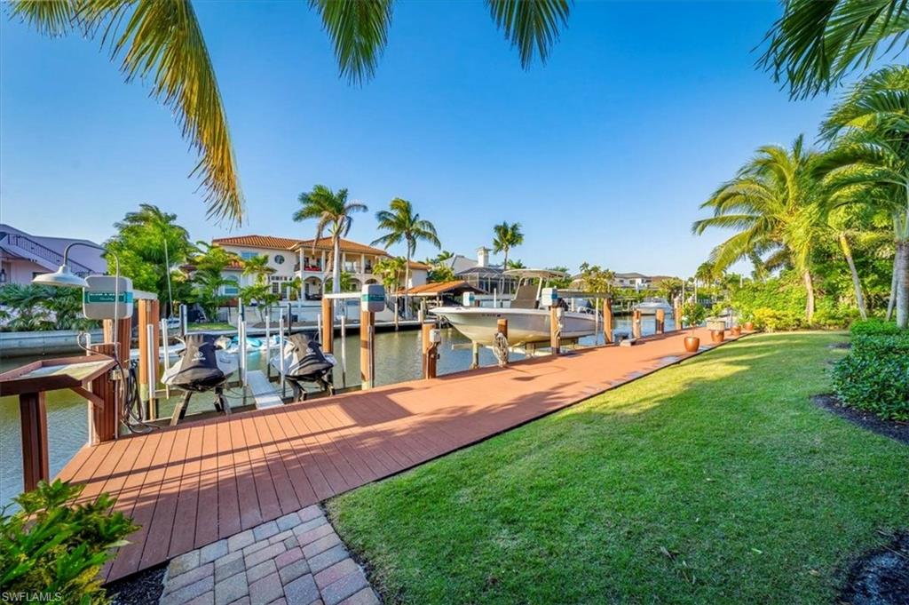 Experience the essence of a Florida lifestyle in this open and inviting waterfront home in one of Naples’ most coveted neighborhoods, Aqualane Shores. The easy living floor plan consists of five bedrooms plus a study and four full bathrooms. The fifth bedroom is upstairs with a full bathroom and at 367 sq ft it can function as a second family room, large guest suite or any number of uses. This remodeled home exudes character with its architectural details including curved archways, volume ceilings, and sets of double sliding doors lining the living and family rooms. The gourmet kitchen is a chef’s delight with two islands, numerous custom cabinets, a butler’s pantry, 5-burner gas stove, two wine or beverage refrigerators and more. Other features include a gas fireplace in the family room, impact resistant doors and windows, and walnut floors throughout. Entertain, grill, and relax while watching a ball game on the private, stylish loggia. This outdoor living space includes a kitchen with bar seating, gas grill, fashionable firepit, and is warmly highlighted by a wood ceiling. The resort-feel continues with a wood accent wall by the large pool, the charming, tiled wall and step fronts, and spa-like outdoor shower. Enjoy easy, bridge-free boating to the gulf from the 84 ft Azek dock which has a 13,000-pound capacity boat lift and double jet ski lift. The superb location is just a few blocks to Naples’ beaches and Third Street South’s celebrated restaurants, shops and farmers’ market.