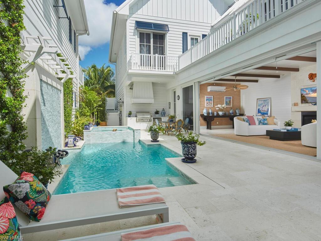 In the heart of Olde Naples, this 2020-built courtyard residence blends timeless coastal architecture with refined, resort-style living just moments from 3rd Street South and Naples’ pristine beaches. Shell-stone travertine floors introduce light-filled living and dining spaces designed for effortless entertaining. The chef’s kitchen is appointed with Sub-Zero refrigeration, Lacanche gas cooking, custom cabinetry, and a thoughtfully designed wet bar. A family room opens seamlessly to the private courtyard, creating true indoor-outdoor living. Upstairs, the serene primary suite offers volume ceilings, tailored millwork, and a spa-inspired bath, joined by two en-suite guest suites and a flexible den/office. A private elevator services both levels. The walled courtyard becomes a secluded retreat with heated plunge pool and spa, outdoor kitchen with built-in grill, surround sound, and lush vertical greenery for privacy. Impact-rated windows and doors, smart-home automation, natural gas, metal roof, and a generous two-car garage with storage complete this thoughtfully engineered residence. Beautifully scaled and impeccably maintained, 909 10th Avenue South offers the rare combination of walkability, architectural integrity, and lock-and-leave ease in Olde Naples.