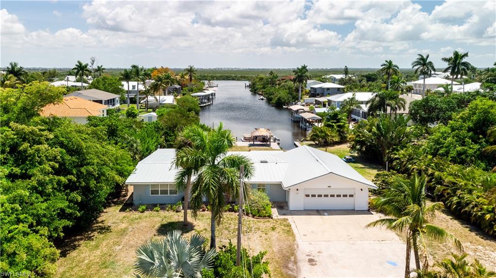 Serenity Cove, Waterfront 3 bedroom 2.5 baths on Large lot... FANTISIC VIEWS looking the entire length of the Canal with Direct access to Matlacha Pass and the Gulf of Mexico !!! Really "cool, artistic interior with unique Master bedroom floor and original Terrazzo, epoxy and floor tile flooring throughout the Home... Open Kitchen with dining bar, Stainless steel appliances with a fisher and Paykel dishwasher drawer, Granite, stainless steel and live edgewood countertops. New LED lighting throughout. Bluetooth speakers in the bathroom ceiling and other unique touches. Check out the lighting in the living area and the open Florida Room...Doors have their own style as does the entire home...   Two porches, one off the master area and the other for guests, beautiful spot for coffee in the morning (and drinks at night), views of the entire Canal, the dock with Tiki Hut, boat ramp and the beautiful Florida Sun. The Garage is a very large two car or truck, (864 Sq ft) with 1/2 bath, plenty of room for shop/storage and other fun garage things !!! Roof New & permitted in 2021
The lot is a LARGE 110' X 170' (almost 1/2 Acre) property with palm and other trees on either side for your privacy and your SERENITY... This is a house you need to see... It's unique, artsy with style and very livable...AND GREAT WATER VIEWS ... Take a look today..