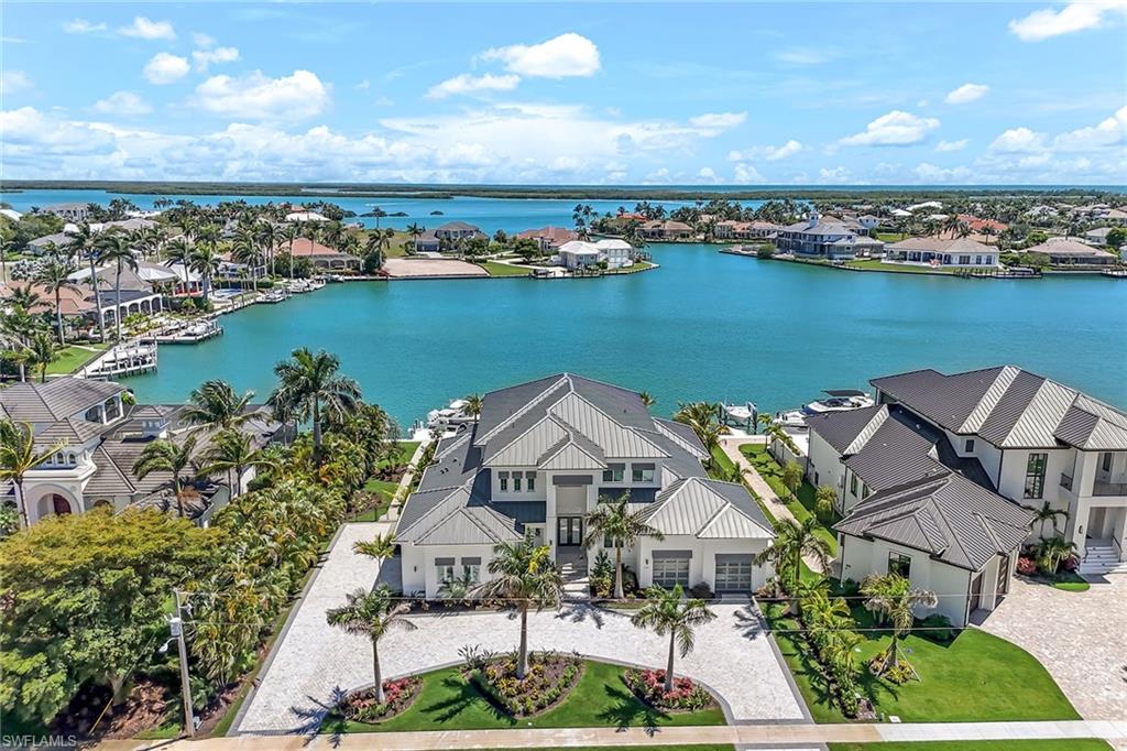 Luxurious, new, custom-built home on a .5-acre lot with southern exposure and stunning wide water views overlooking Fredericks Bay. In mint condition, this home has designer finishes throughout and features four bedrooms plus a large office/den, five full baths, resort-style pool plus integrated spa, elevator, four-car garage (one with air conditioning) with additional room for lifts, 60,000-pound boat lift and two platform lifts for jet skis and a tender. Chef-style kitchen with Sub-Zero & Wolf appliances, custom cabinetry, quartz counters, designer fixtures and a walk-in pantry. Adjacent to the kitchen is a fabulous dining area with a built-in wet bar and an oversized Sub-Zero wine cellar. Expansive great room with soaring ceilings, built-ins, intricate ceiling details and views in every direction. Designed with a coastal lifestyle in mind, the home has sliding pocket doors to optimize for seamless indoor/outdoor living. Outdoor entertaining is made easy with a custom bar/summer kitchen, sprawling lanai, fireplace and hurricane shutters plus electronic screens. Primary bedroom on the first floor with dual closets and spa-like bathroom with dual shower heads and soaker tub. The second floor has a great room with incredible bay views, three sizable bedrooms, three full baths, a bar and large lanai. Other features include wide plank white oak flooring throughout, Uxari Home Security System, elevator, laundry room with two full-size washer and dryers, sink, ample storage and a generator. Direct access out to the Gulf in just minutes. Island living is calling your name!