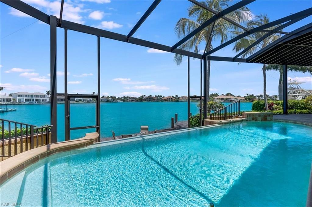 WIDE OPEN WATER VIEWS from a prime location on Marco Island… A coveted lot with a beautiful 3455 Square foot Pool home at the end of a cul-de-sac, which provides 161 feet of water frontage and all the benefits a boating enthusiast would want. Bring ALL your boats- with TWO  boat lifts and endless dock space. These owners housed their 18’ fishing boat and a 33’ Grady White on the other. The dock is made out of Azobe, which is an extremely dense and heavy hardwood that is highly resistant to saltwater, marine borers and decay. The Ten Thousand Islands are your neighbors. Preferred by most boaters for their endless private beaches you can claim as your own and a fisherman’s paradise. A thoughtfully designed home, for the family who enjoys the water, has a backside garage entrance with A/C for the storage of fishing poles, water toys, bikes and anything needed- conveniently located for a boating day. Watch the dolphins jump in the bay from your lanai, the dock, the pool deck, or the 2nd story balcony. Fish off your own dock, that comes equipped with a snook light. And what’s more about the location of this property is it is walking distance to restaurants, resorts, shopping and some of the most beautiful white sandy beaches in all of Southwest Florida. This two-story home is thoughtfully designed for both comfort and flexibility, with five bedrooms and a den with 5 bathrooms! It features TWO primary bedroom suites, one on the main level and one upstairs making it ideal for guests or multi-generational living. The home is perfectly oriented to capture sunny mornings and shaded afternoons over the newly rescreened lanai and infinity edge pool, creating an inviting outdoor space to enjoy Florida living year-round. Upstairs, a private balcony extends across the entire back of the home, providing a peaceful, sunlit retreat. A nearby marina makes it easy to fuel up the boat or pick up bait before heading out on the water, while your own backyard dock offers the chance to watch incredible marine life up close. This is a rare opportunity to enjoy a premier waterfront lifestyle in one of the island’s most desirable locations.