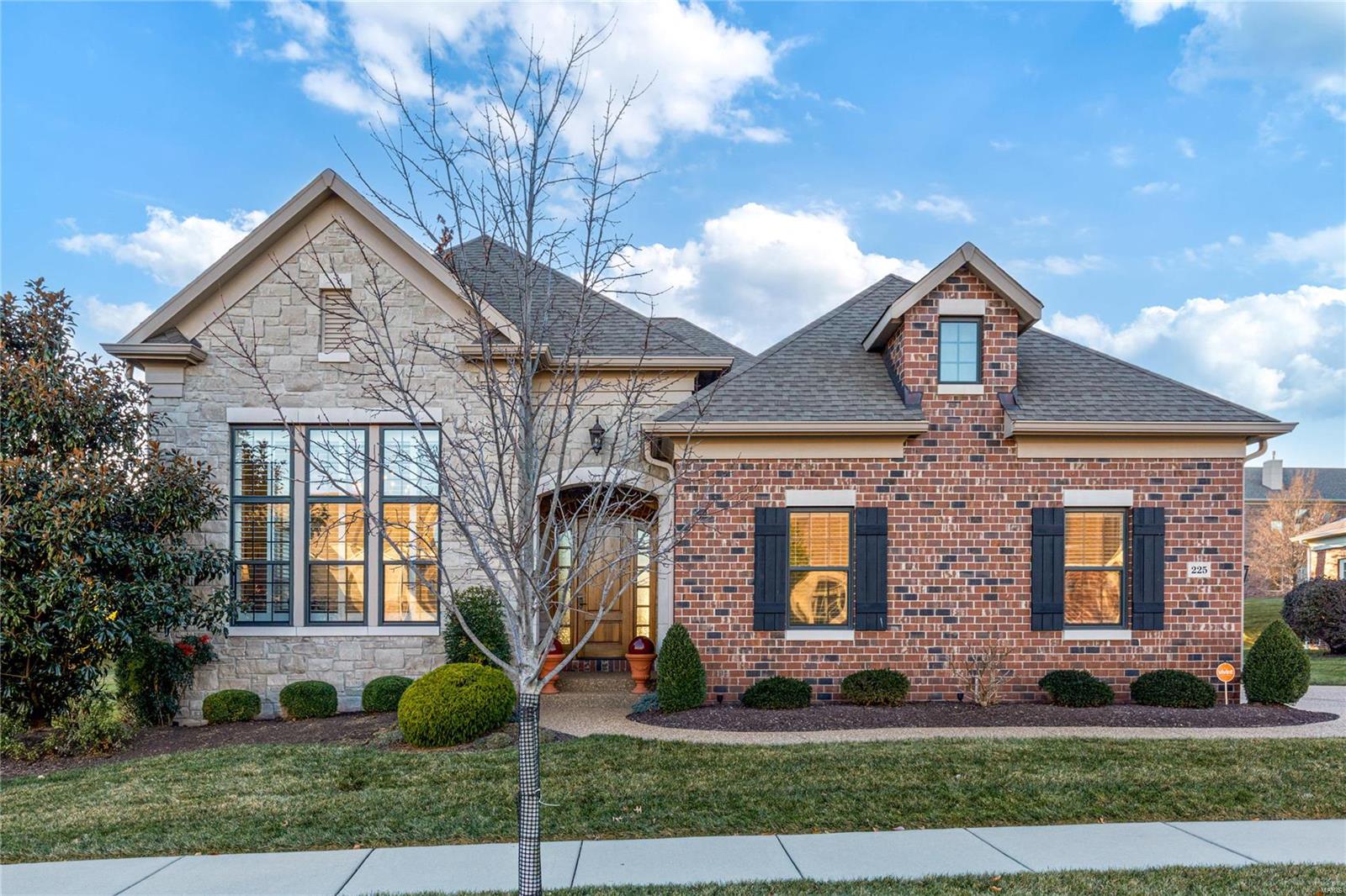 This exquisite brick & stone great room ranch from Simon Homes redefines luxury living. Beautifully designed 4846 sf “Avalon” model features soaring ceilings, detailed trim work, designer lighting & oak hardwoods that extend throughout the main floor. Barrel-vaulted entry foyer leads to well-appointed study/ensuite bedroom, formal dining room framed by architectural columns & stunning great room with 14’ ceiling, marble fireplace, built-in bookcases & dramatic bank of windows. Designer kitchen with quartz countertops, white cabinetry, premium appliances & 10’ center island adjoins light-filled breakfast room that opens to patio. Coffered primary bedroom suite with luxury bath offers an appealing retreat. Lower Level includes recreation room, family room with direct vent fireplace, gathering bar, 3rd & 4th bedrooms & full bath. Enjoy carefree living with included lawn maintenance, snow removal & irrigation system. Premier gated community with walking trails, ponds, fountain & waterfall.