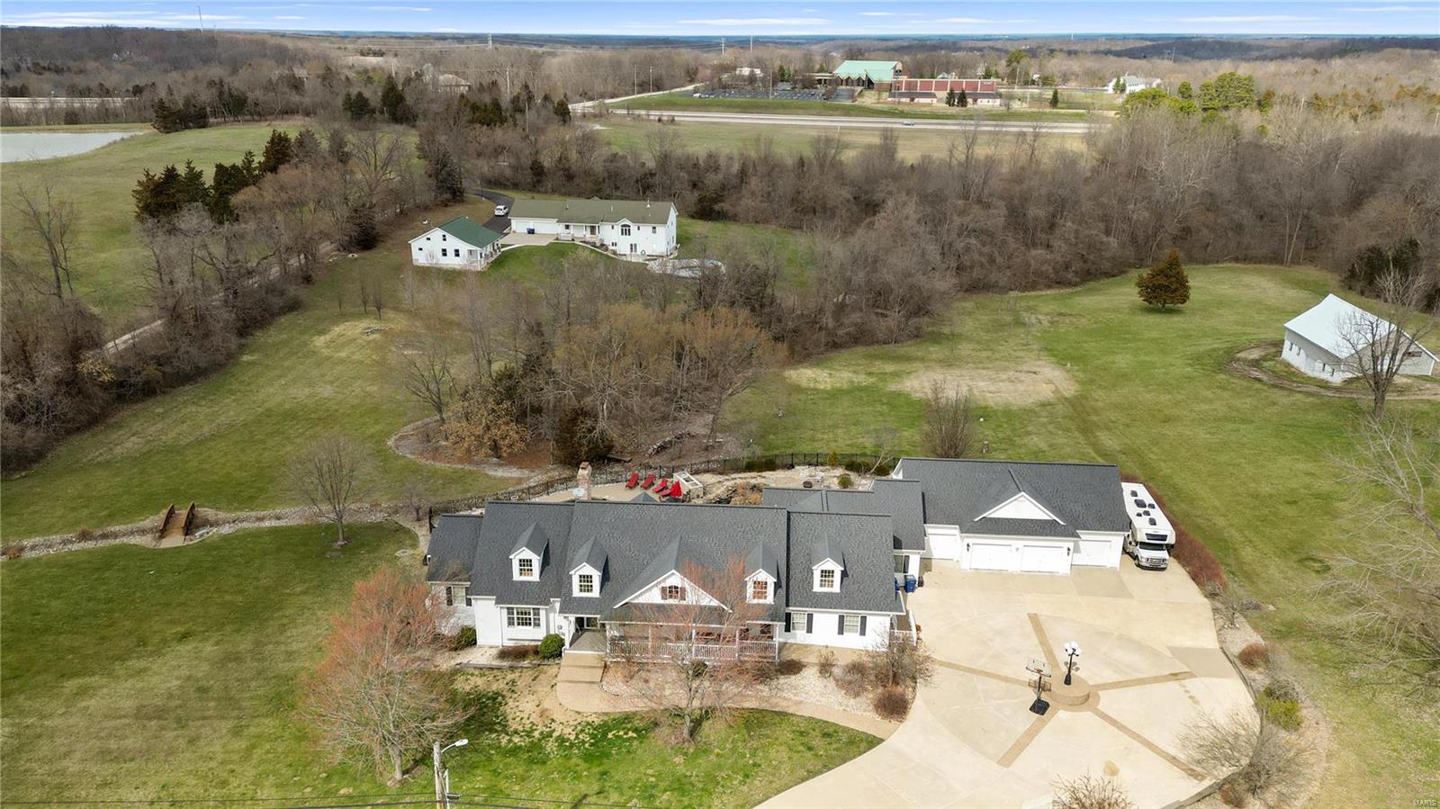 You don’t want to miss this STUNNING 6 bed, 4.5 bath, custom great room ranch on 3 acres with a pool, golf tee and 4 car garage in Wildwood! The perfect guest/in-law wing features a living area, separate kitchen area, bedroom and full bath.  Great room with vaulted ceiling, wall of windows & a wood burning fireplace. The kitchen features custom cabinets, center island, walk-in pantry, granite counters, stainless steel appliances & breakfast room. Spacious wood lined 3 season room with leads to deck overlooking gorgeous backyard oasis. Main floor master suite with walk-in closets, dual vanities & a soaking tub.  Additional spacious bedroom/office, full bath and laundry room.. You must see the finished walk-out lower level! Rec room with full bar, additional family room with 2nd stone fireplace.  3 additional bedrooms & 2 full baths complete the space. The expansive backyard offers the heated pool, hot tub, waterfalls, koi pond and outdoor kitchen for the ultimate outdoor experience. Additional Rooms: Mud Room, Sun Room