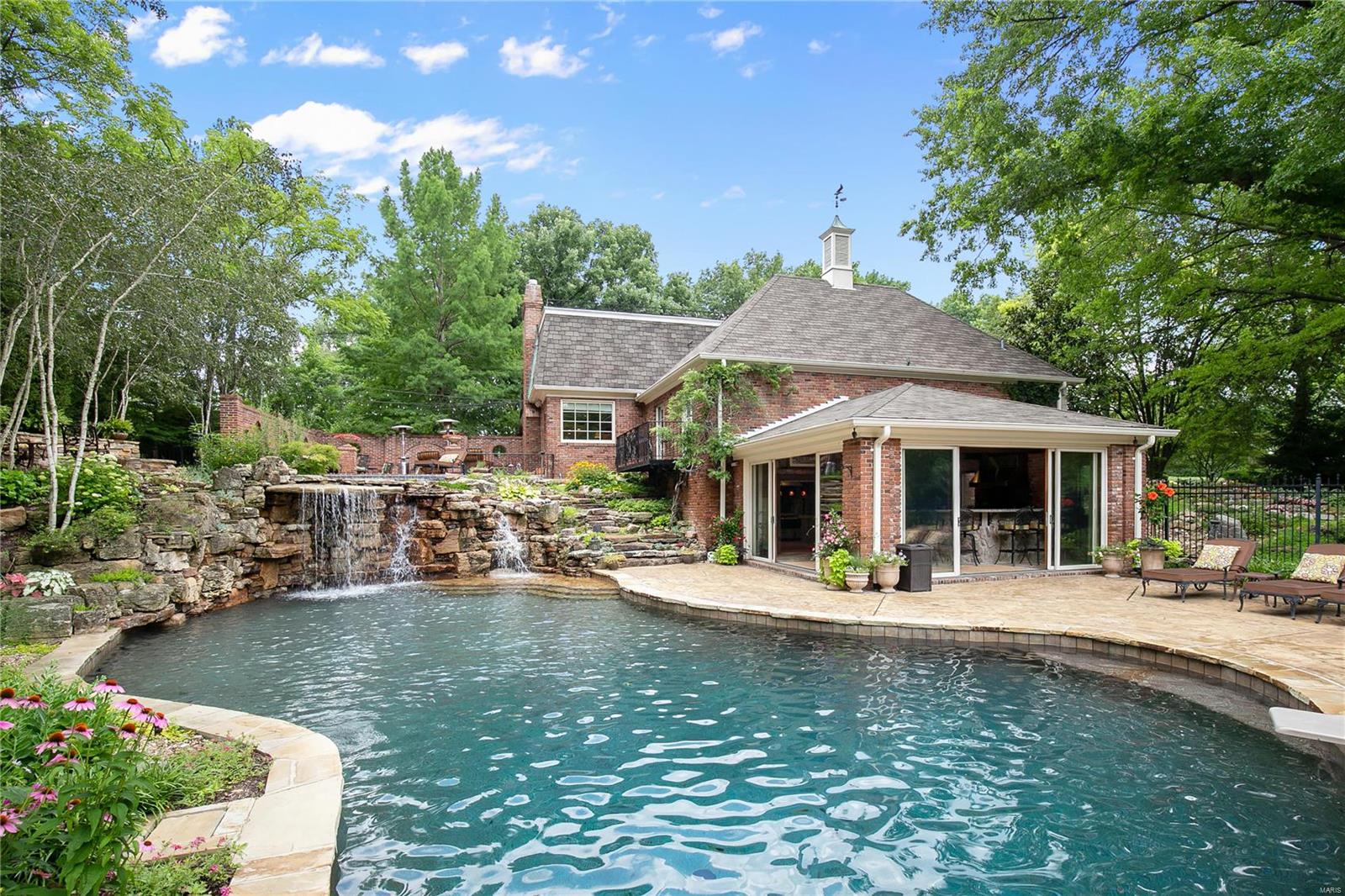 This timeless designed 1.5 story is situated on a private 1.8 acre wooded lot in the Heart of Ladue. Resort living & filled w surprises including lux pool & spa w one-of-a-kind rock waterfall! Lower level features vaulted pool house/kitchen, grill & bar area. Plus vine covered pergola w TV & stone fireplace! Firepit area for cool nights all this surrounded by lush landscaping. 2 story entry foyer opens to elegant Din rm &  Liv rm. Stunning vaulted/ beamed Great rm w flr to ceiling frpl & mini bar. Gourmet Kitchen w center island & French drs opening to tranquil brick terrace. Private light filled office w French drs to  add. patio. Spacious beamed Master Suite w stone fireplace, custom remodeled bath & French drs open to wrought iron balcony overlooks pool. 2 half baths, Butler’s pantry, Laundry rm & lockers complete main. 4 bdrms & 2 baths on 2nd. The LL is a rare gem complete w family/media rm, 26x22 rec rm, full bath w changing rm, & office/guest bdrm. Truly an entertainer’s dream!