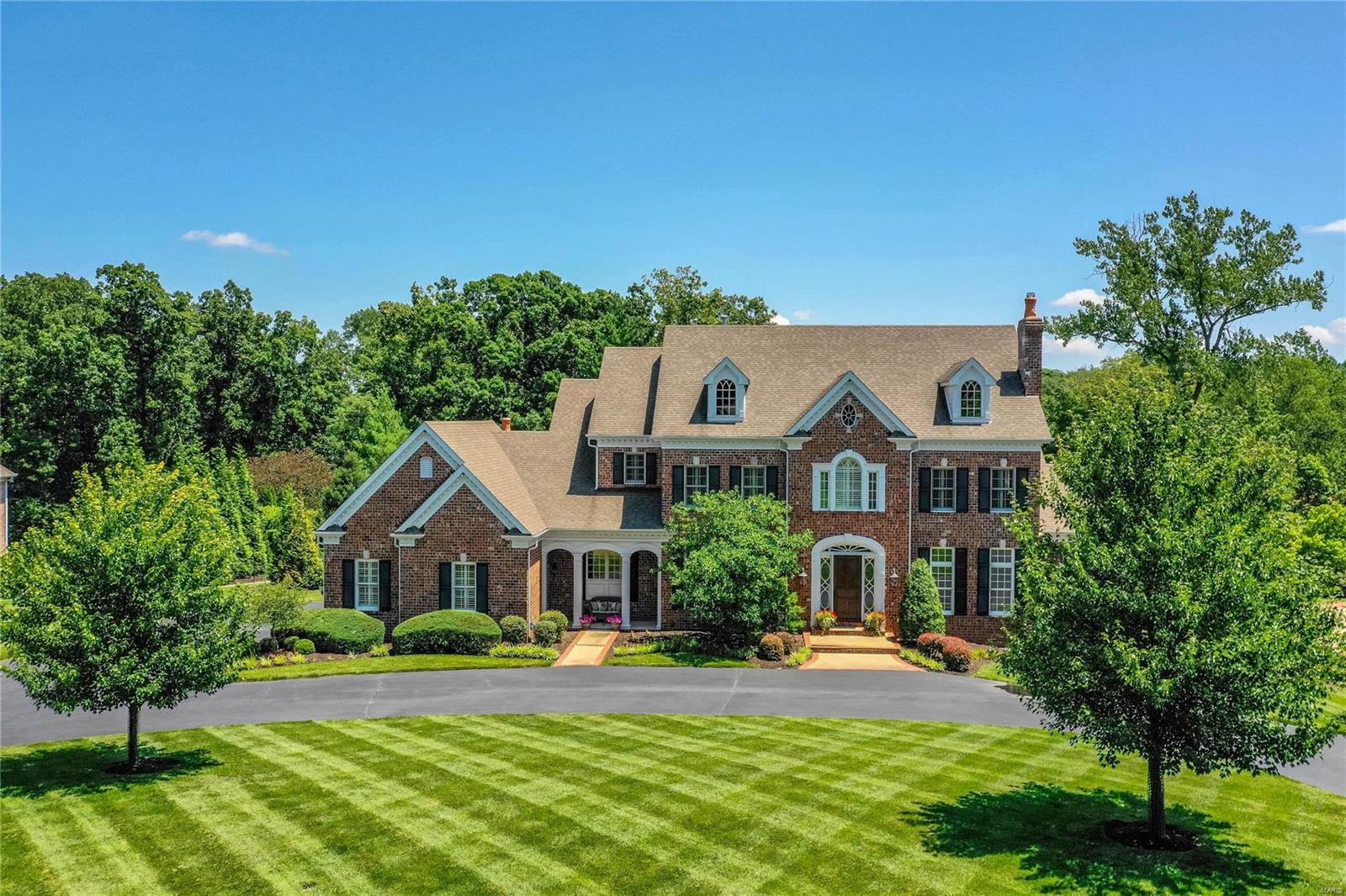 A truly magnificent brick 1.5 Sty from award-winning builder Bruning Homes! Impressive travertine marble foyer leads to library-paneled study with custom built-ins & slate fireplace with handcrafted mantel, elegant dining room & stunning great room with 15’ ceiling, marble fireplace & dramatic wall of windows. Designer kitchen with granite countertops, natural cherry cabinetry, commercial grade appliances & butler’s pantry adjoins light-filled breakfast room, hearth room with stone fireplace & 2 sets of French doors to screened porch & vaulted gathering bar. Sumptuous master bedroom suite with sitting area & marble bath with shower spa & jetted tub offers an appealing retreat. Front & rear staircases access 3 additional ensuite bedrooms & bonus room. Lower Level includes recreation room with wet bar & stone fireplace, game room & wine cellar plus office, 5th & 6th bedrooms & full bath. French doors open to outdoor living area with fireplace, grill station, hot tub & resort style pool. Additional Rooms: Wine Cellar