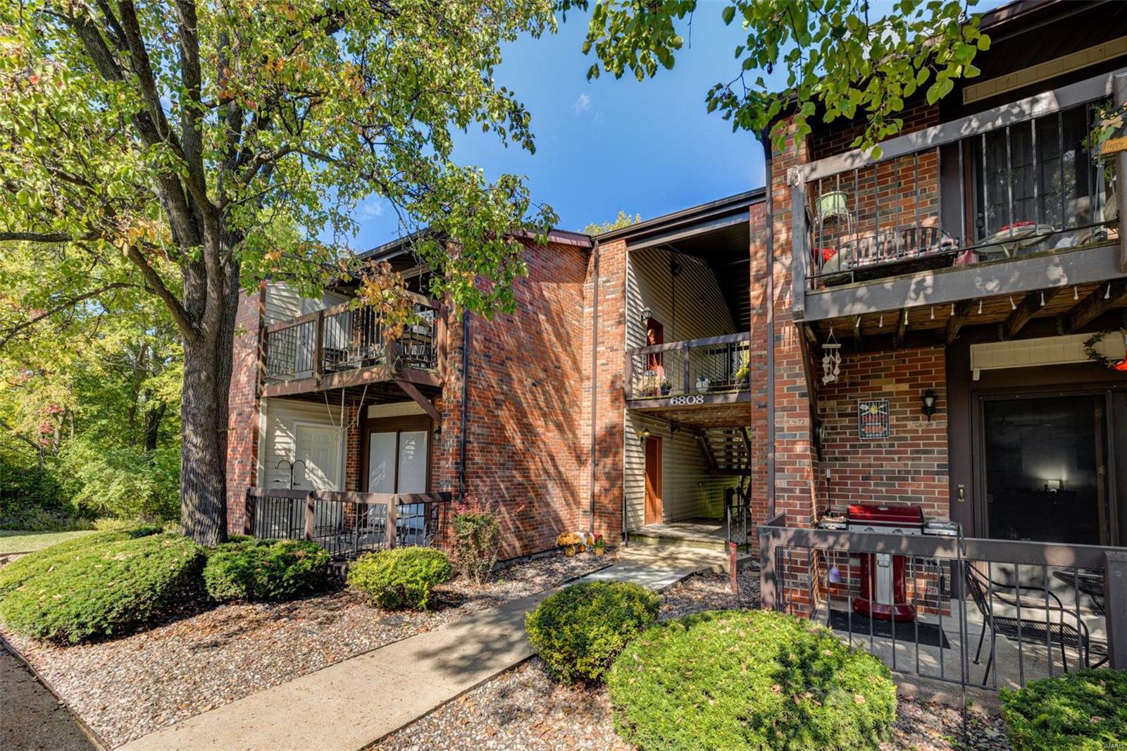 Upper level brick condo with vaulted ceilings that backs to common ground and woods in desirable New England Village. 2 beds, 1 bath and in-unit laundry w/stackable washer/dryer that stay. Open floor plan w/living room featuring woodburning fireplace, vaulted ceilings, and slider to storage room and private deck overlooking woods. Breakfast room with vaulted ceiling and ceiling fan just off kitchen w/electric range, garbage disposal, dishwasher, pantry and refrigerator that stays. Owner's suite includes expansive closet, and amazing wooded view. Second bedroom and full bath with in-unit laundry. 6-panel doors and a covered parking spot. Short walk to clubhouse, tennis courts, basketball court and pool for annual fee of $325. Monthly condo fee of $208 includes water, sewer, trash, snow removal, lawn/landscaping, etc. Oakville schools and close proximity to restaurants, shopping and retail. Location: End Unit, Upper Level